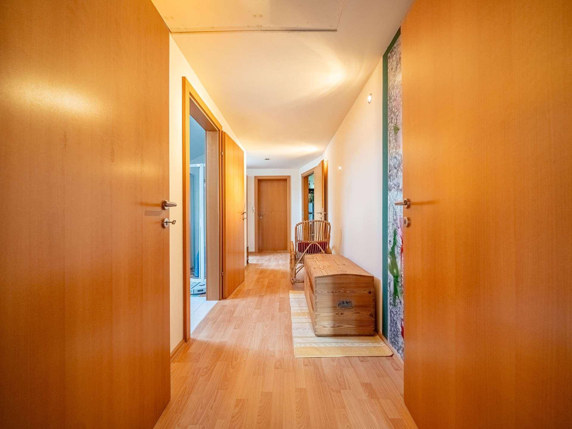Heller Flur mit Holzfurniertüren und Laminatboden, der zu weiteren Räumen führt.