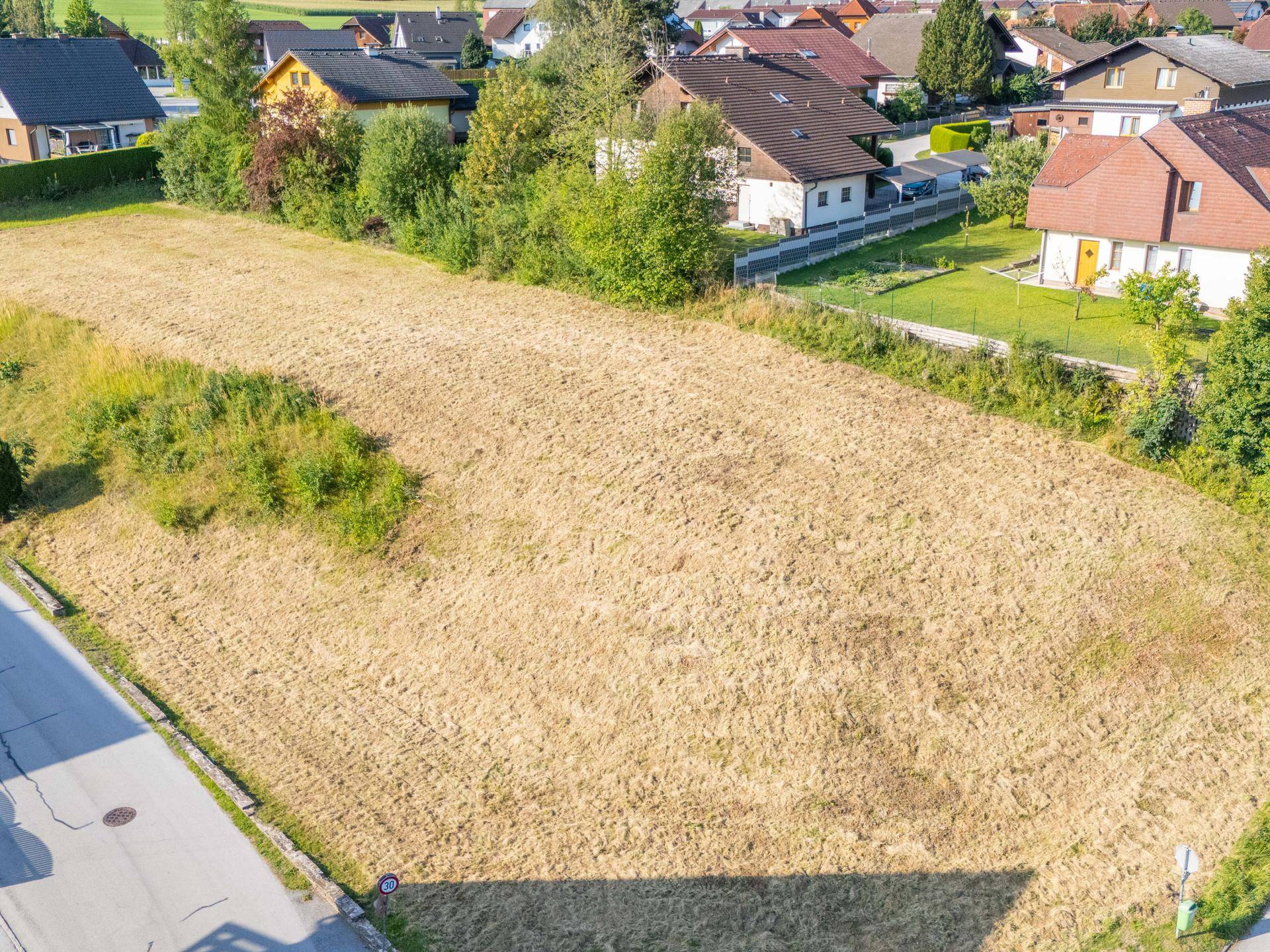 Weitläufiges Grundstück in einer Wohnsiedlung, umgeben von Einfamilienhäusern und viel Grün.
