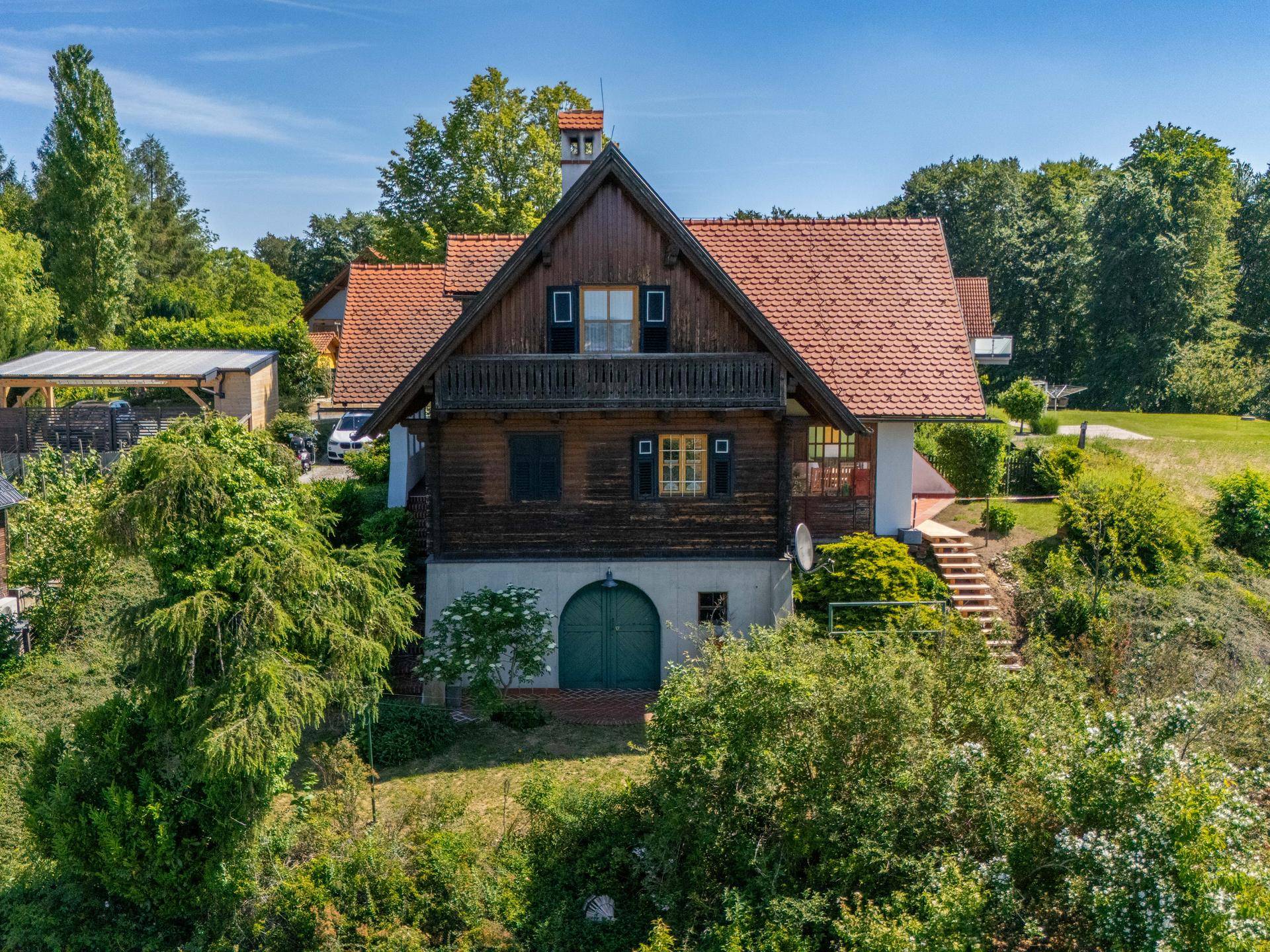 Charmantes Chalet-Haus mit Holzfassade, rotem Ziegeldach und üppiger grüner Umgebung.