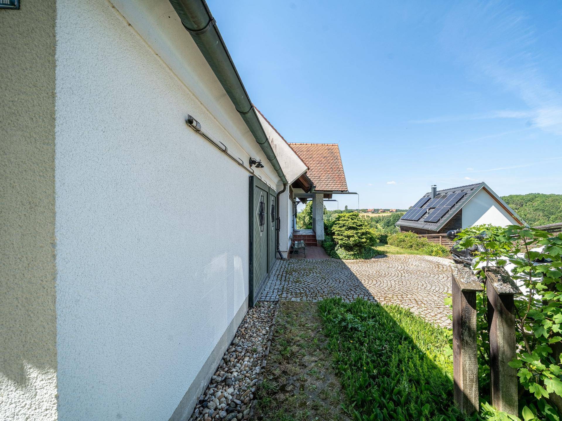 Gepflasterte Auffahrt mit Kopfsteinpflaster, die zur Garage führt, umgeben von Grün.