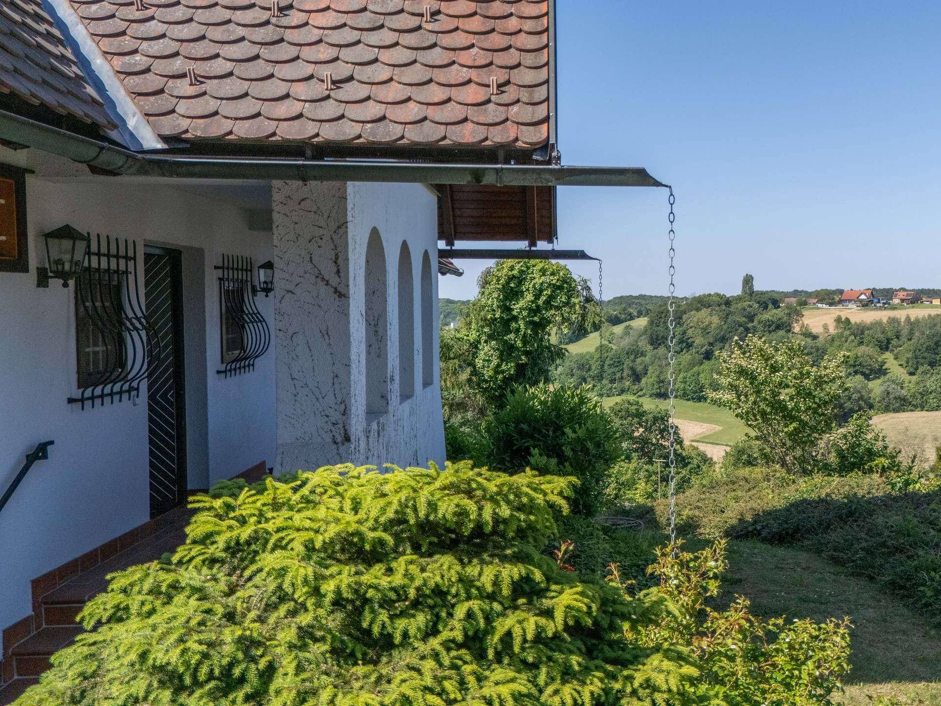 Detailansicht der Hausfassade mit Bogenfenstern und weitem Blick über die hügelige Landschaft.
