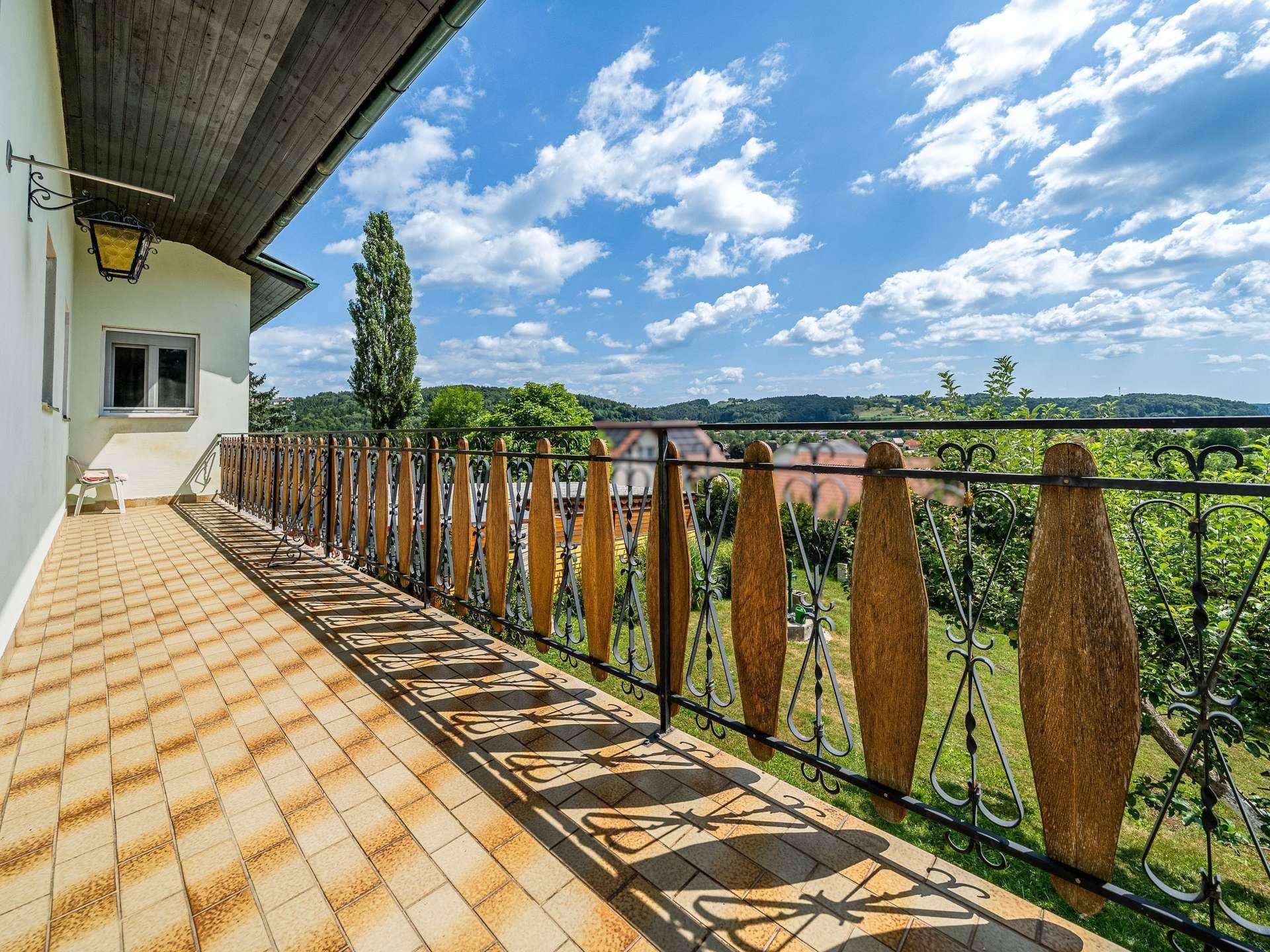 Langer Balkon mit Fliesenboden und schmiedeeisernem Geländer bietet weite Aussicht.