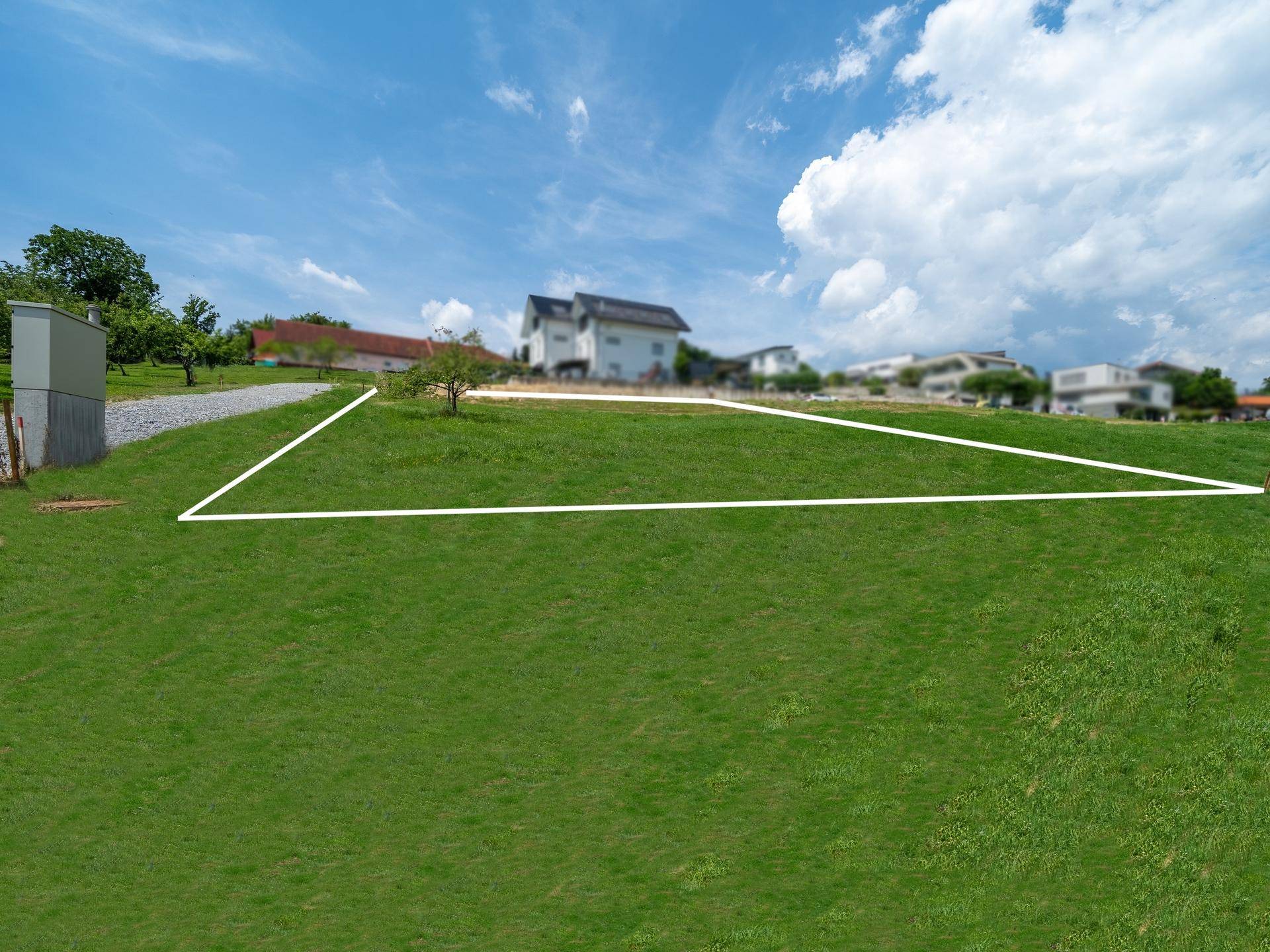 Weitläufiges grünes Grundstück mit markierten Grenzen und modernen Wohnhäusern im Hintergrund.