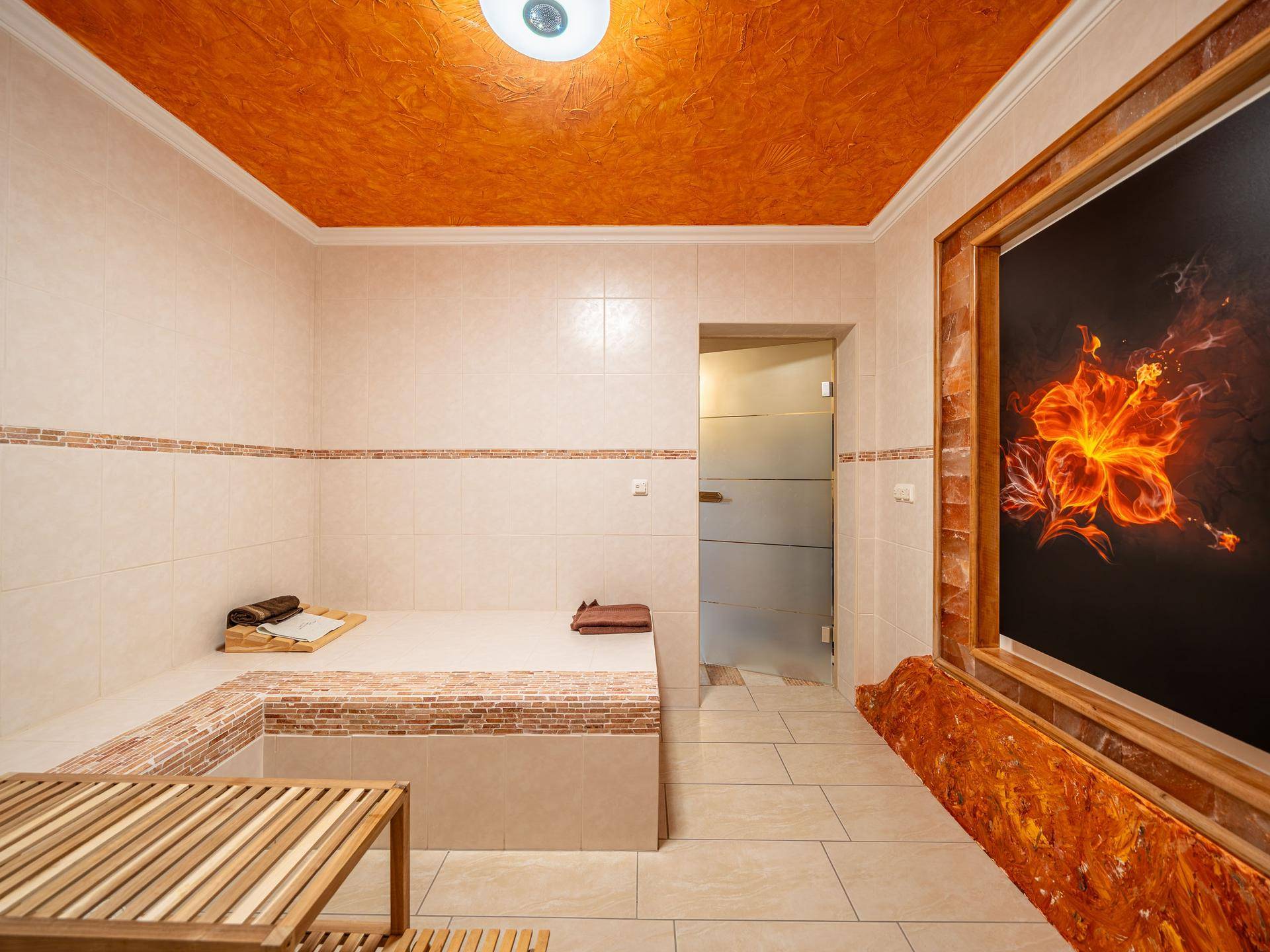 Wellnessbereich mit gefliesten Sitzgelegenheiten und einer warmen, orangefarbenen Decke.
