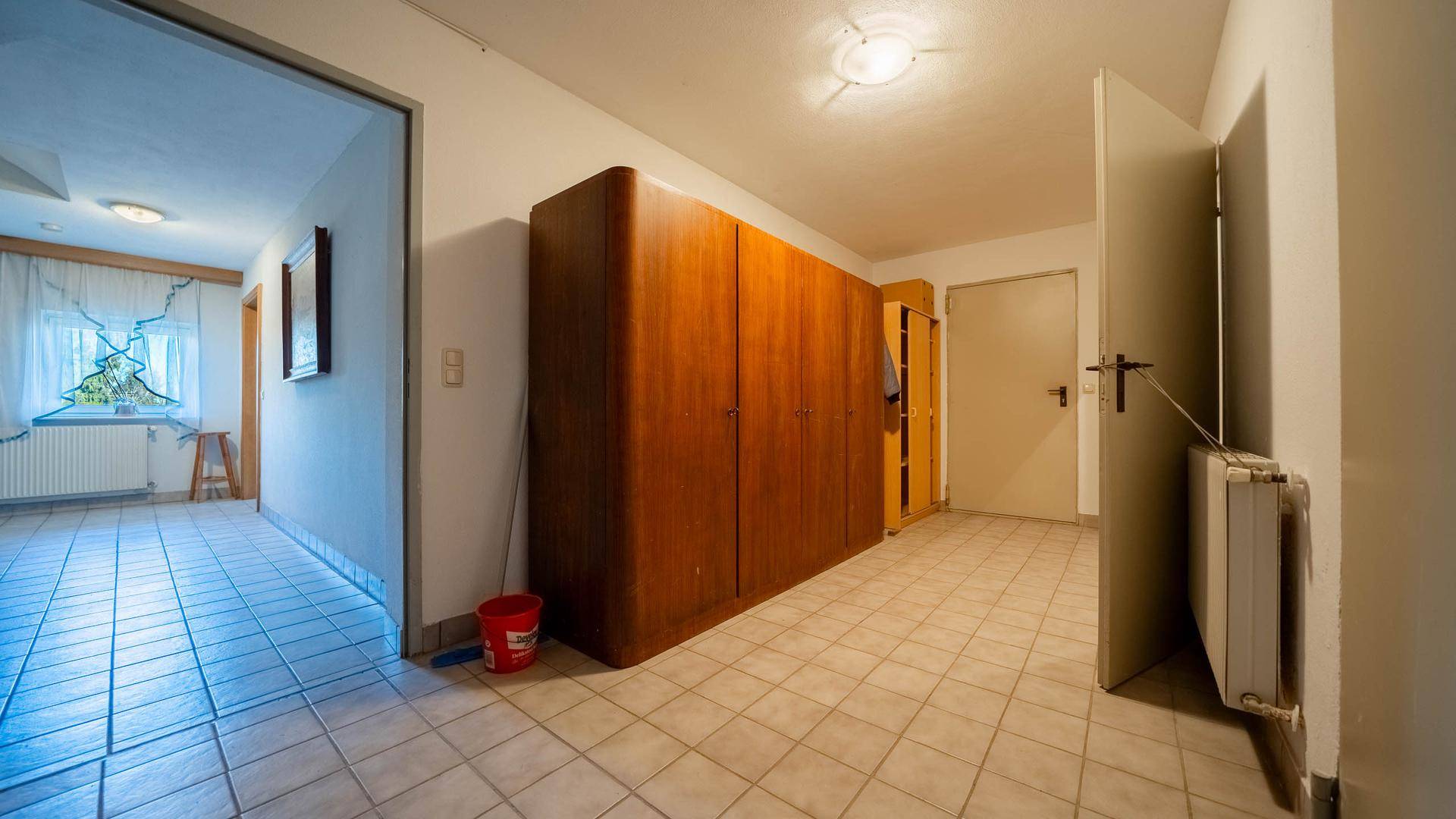 Kellerflur mit Fliesenboden, großem Schrank und Zugang zu weiteren Räumen.