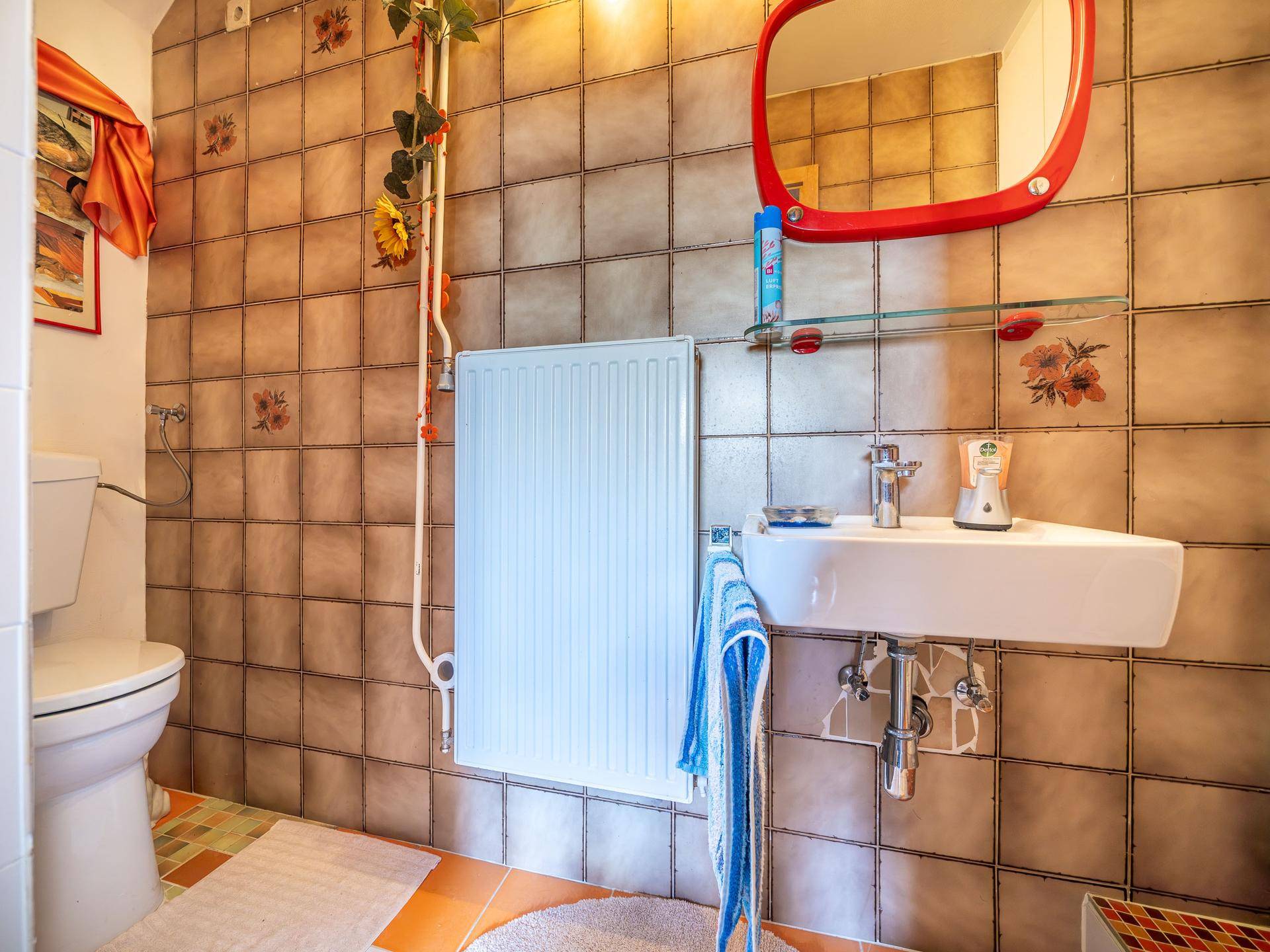 Gäste-WC mit braunen Fliesen, Waschbecken und Toilette, funktional und sauber.