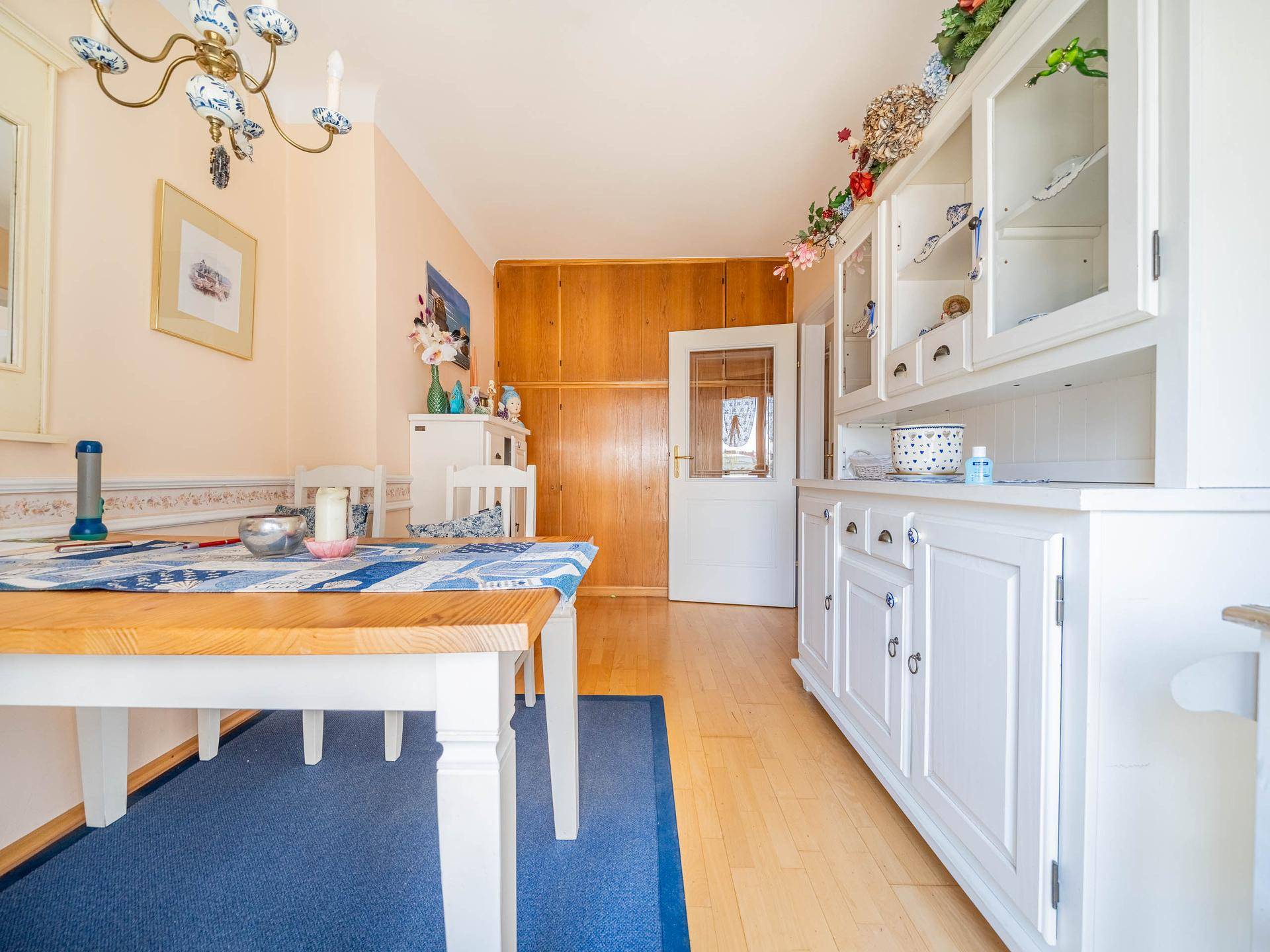 Essbereich mit Holztisch, weißem Buffet und Holzvertäfelung an der Wand.