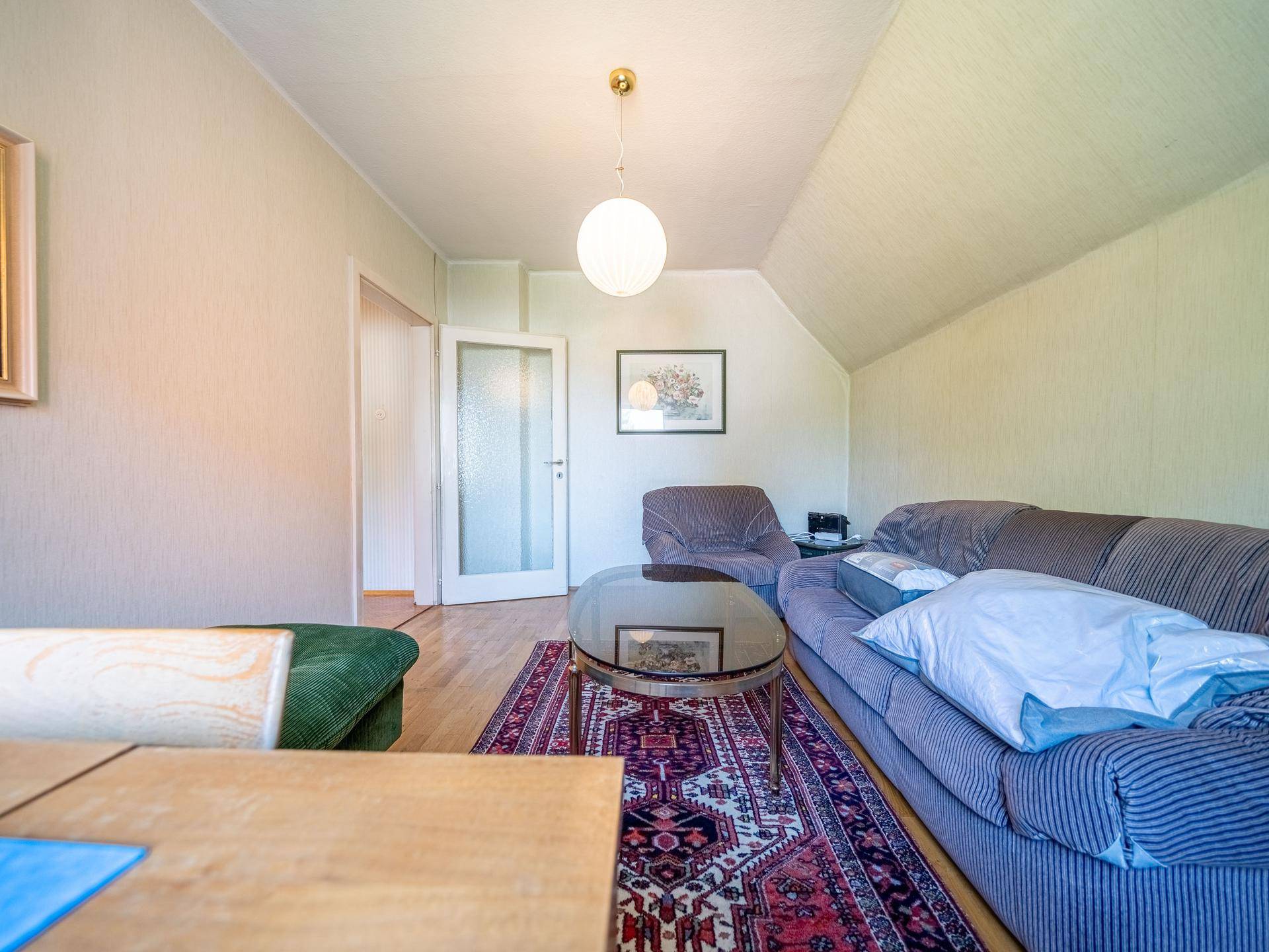 Dachgeschoss-Wohnzimmer mit Sofa, Couchtisch und hellem Parkettboden.