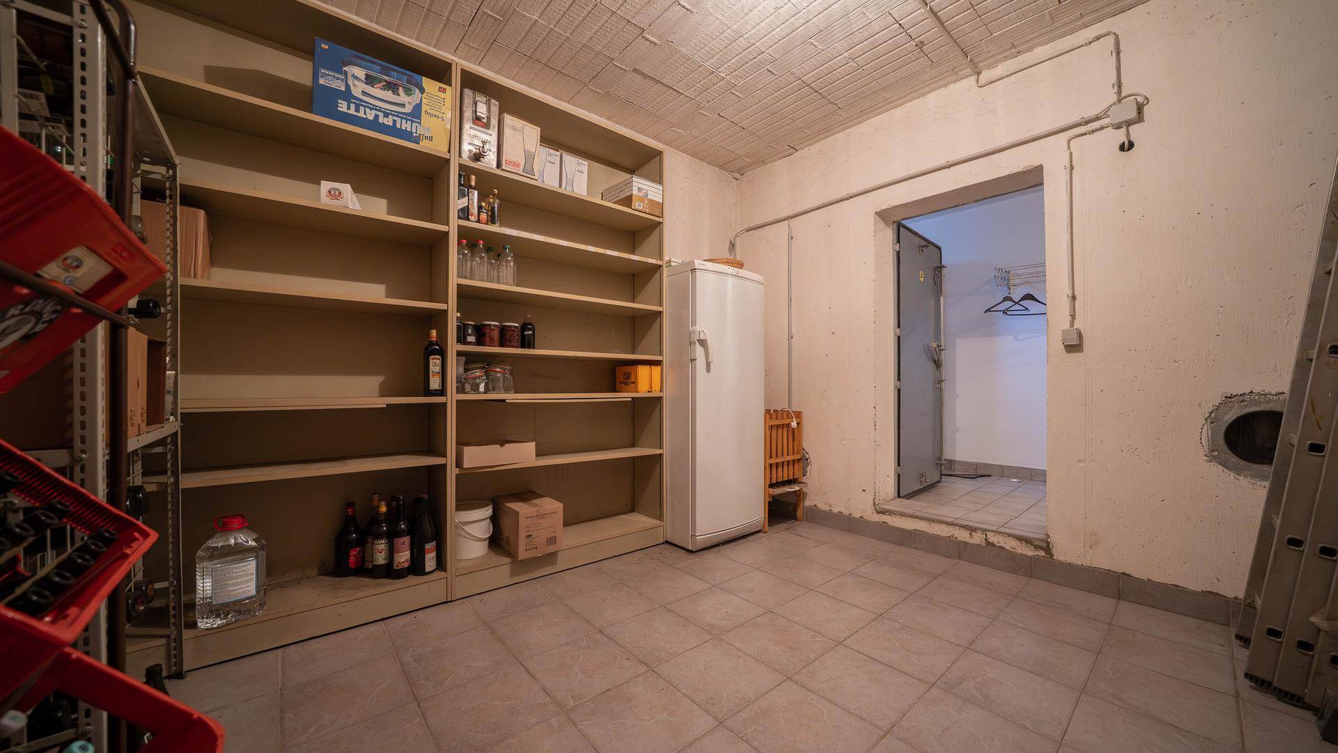 Weinkeller mit Regalen, Flaschen und einem Kühlschrank für die Lagerung.