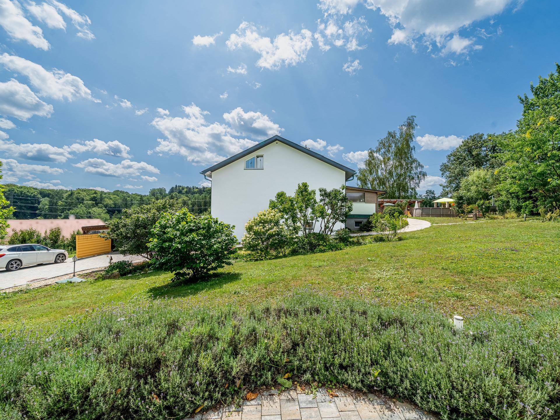 Seitenansicht des Hauses mit weitläufigem Rasen und üppiger grüner Landschaft.