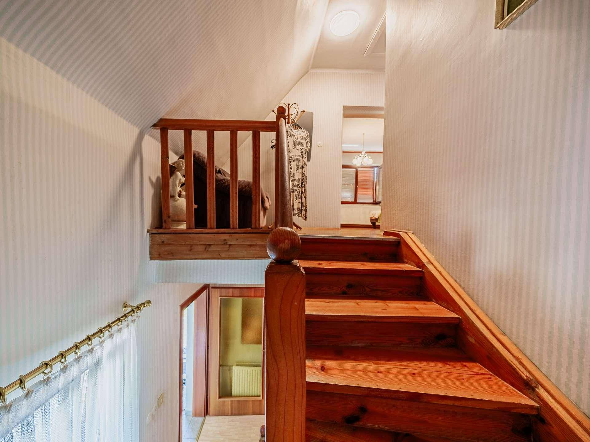 Helle Holztreppe führt in das Obergeschoss, mit Blick auf den darunterliegenden Flur.