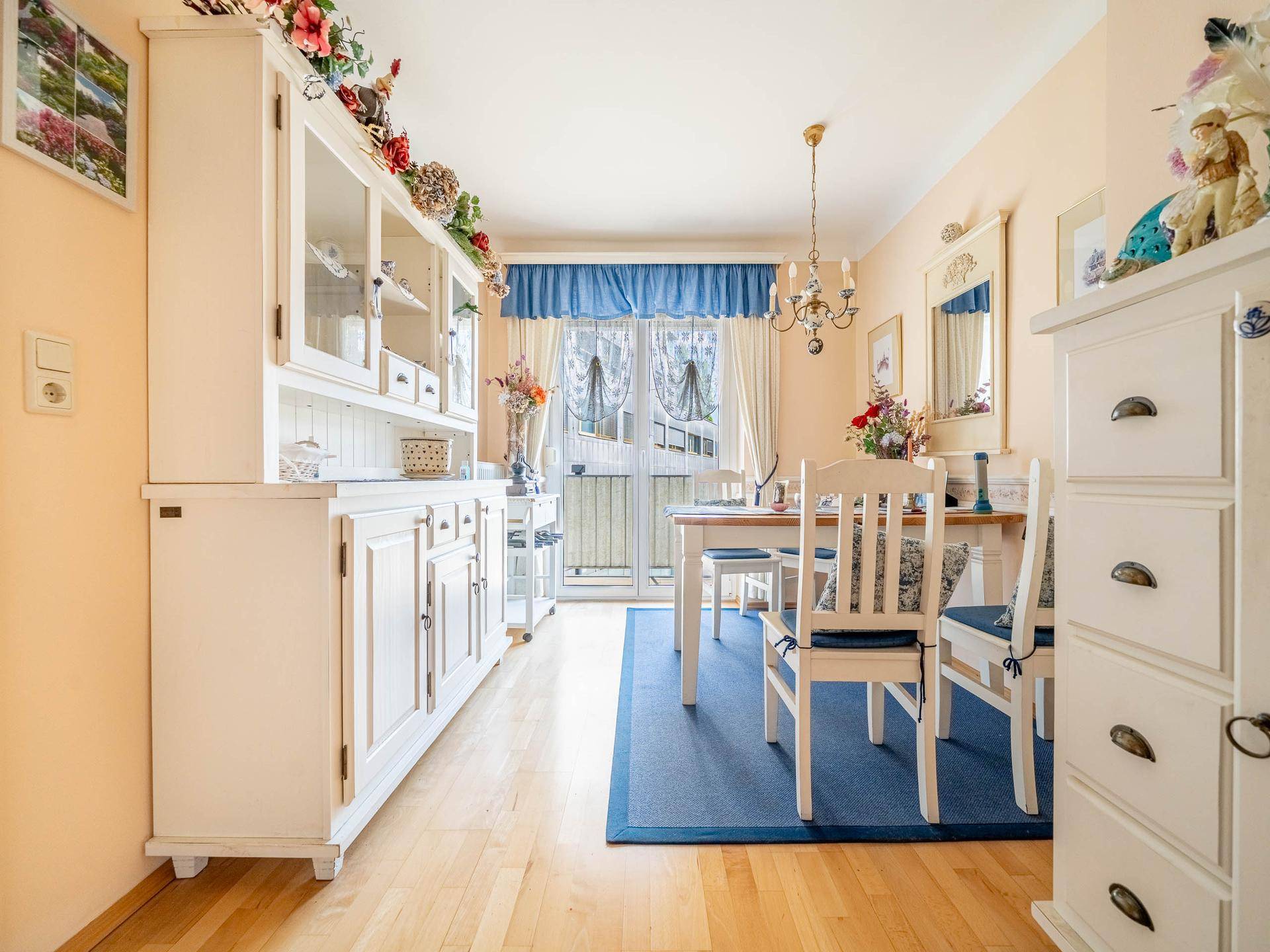 Heller Essbereich mit Holzboden, weißem Buffet und Zugang zum Balkon.