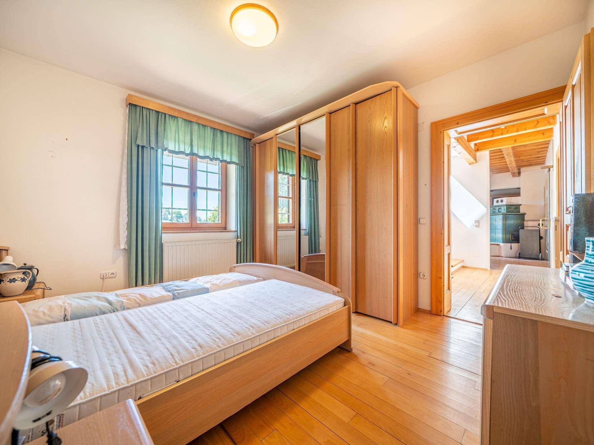 Helles Schlafzimmer mit Holzboden, großem Kleiderschrank und Blick auf die grüne Umgebung.