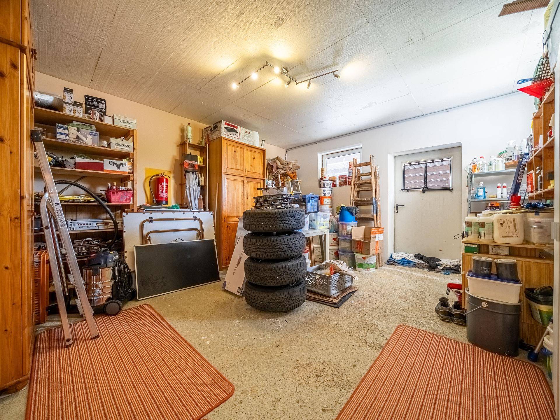 Geräumige Garage oder Werkstatt mit viel Stauraum, Werkzeugen und Reifen.