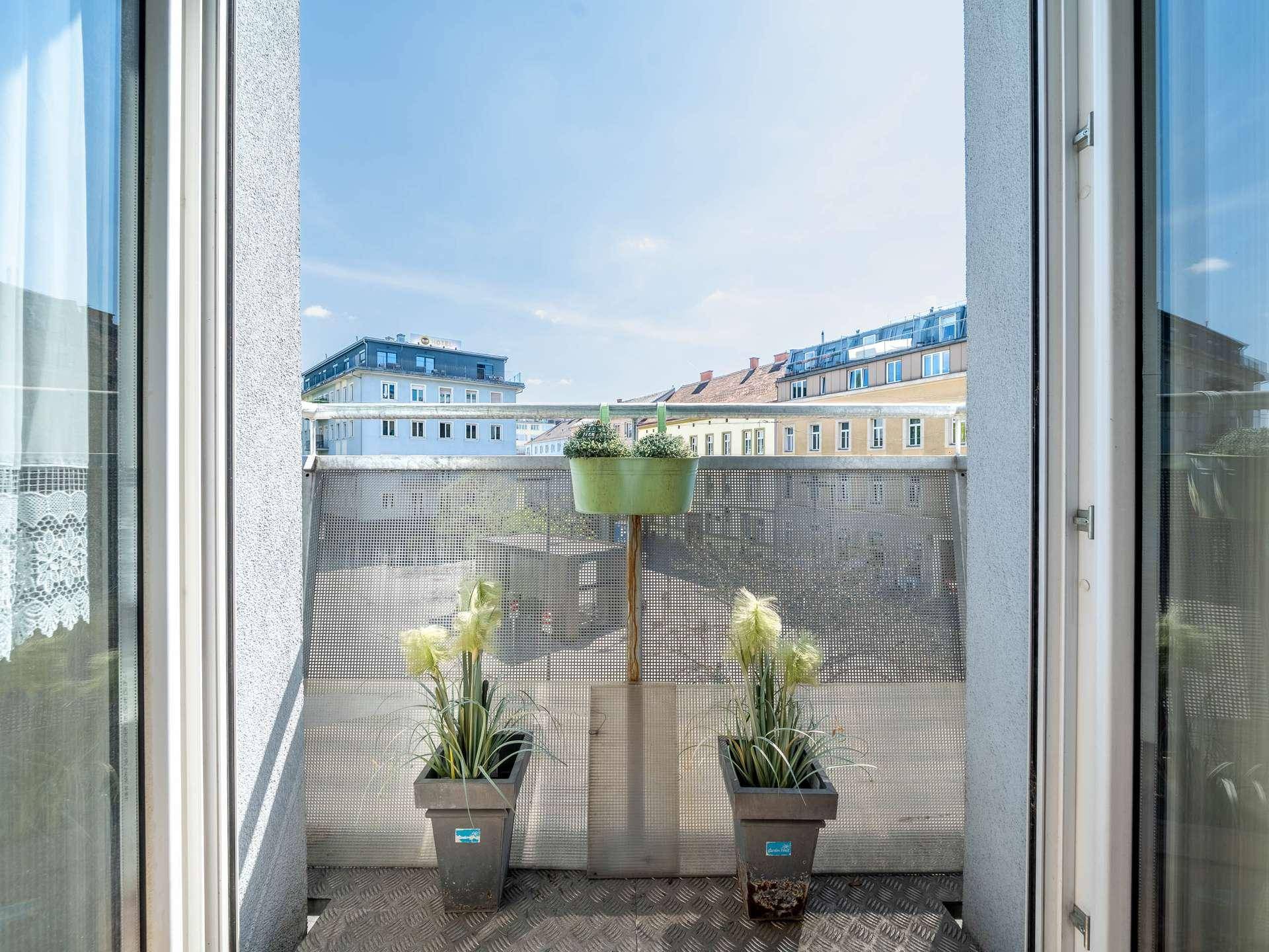 Kleiner Balkon mit Pflanzen und Blick auf die umliegenden Gebäude.