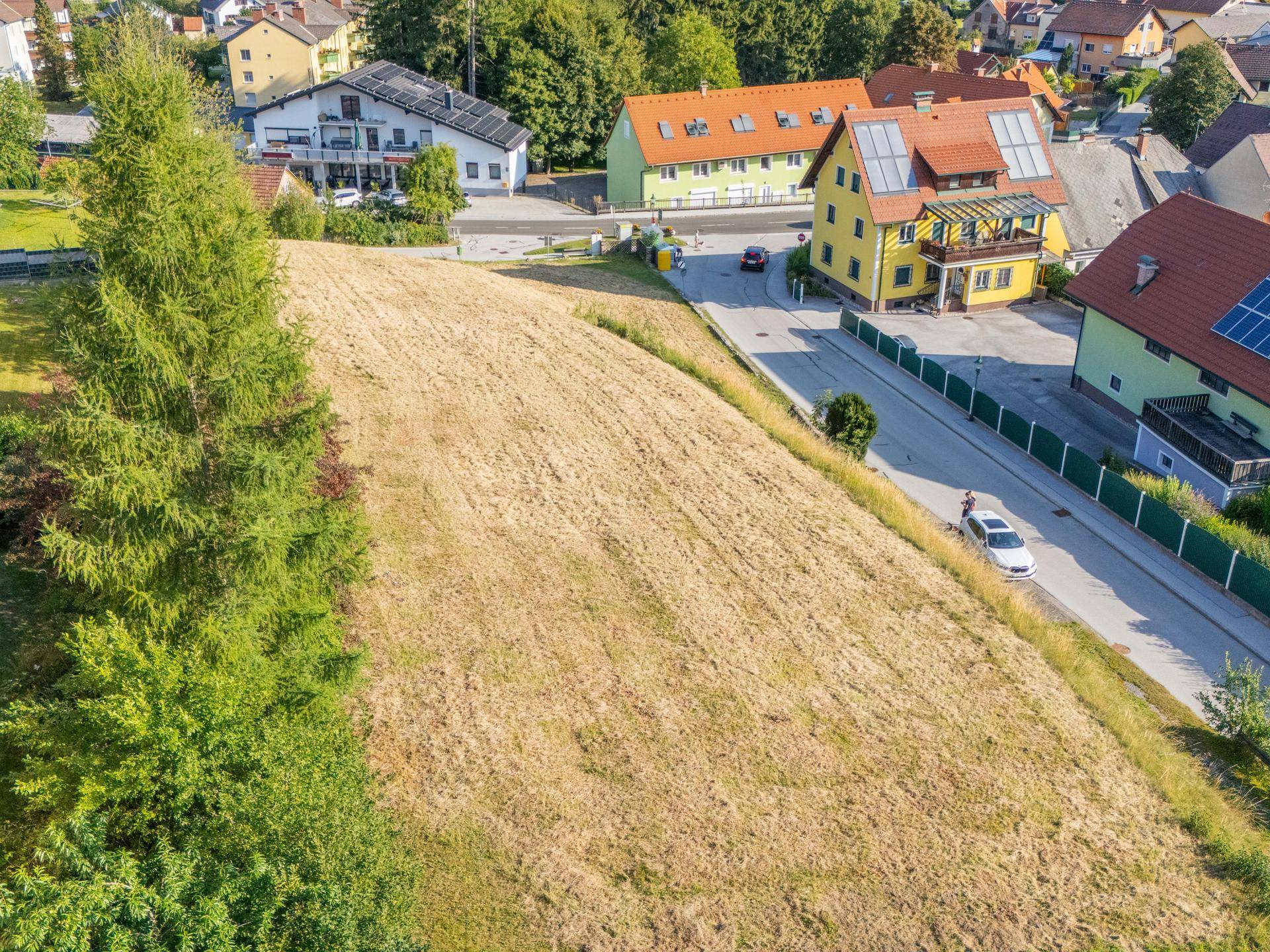 Großes Grundstück mit leichter Hanglage, angrenzend an eine ruhige Wohnstraße und weitere Häuser.