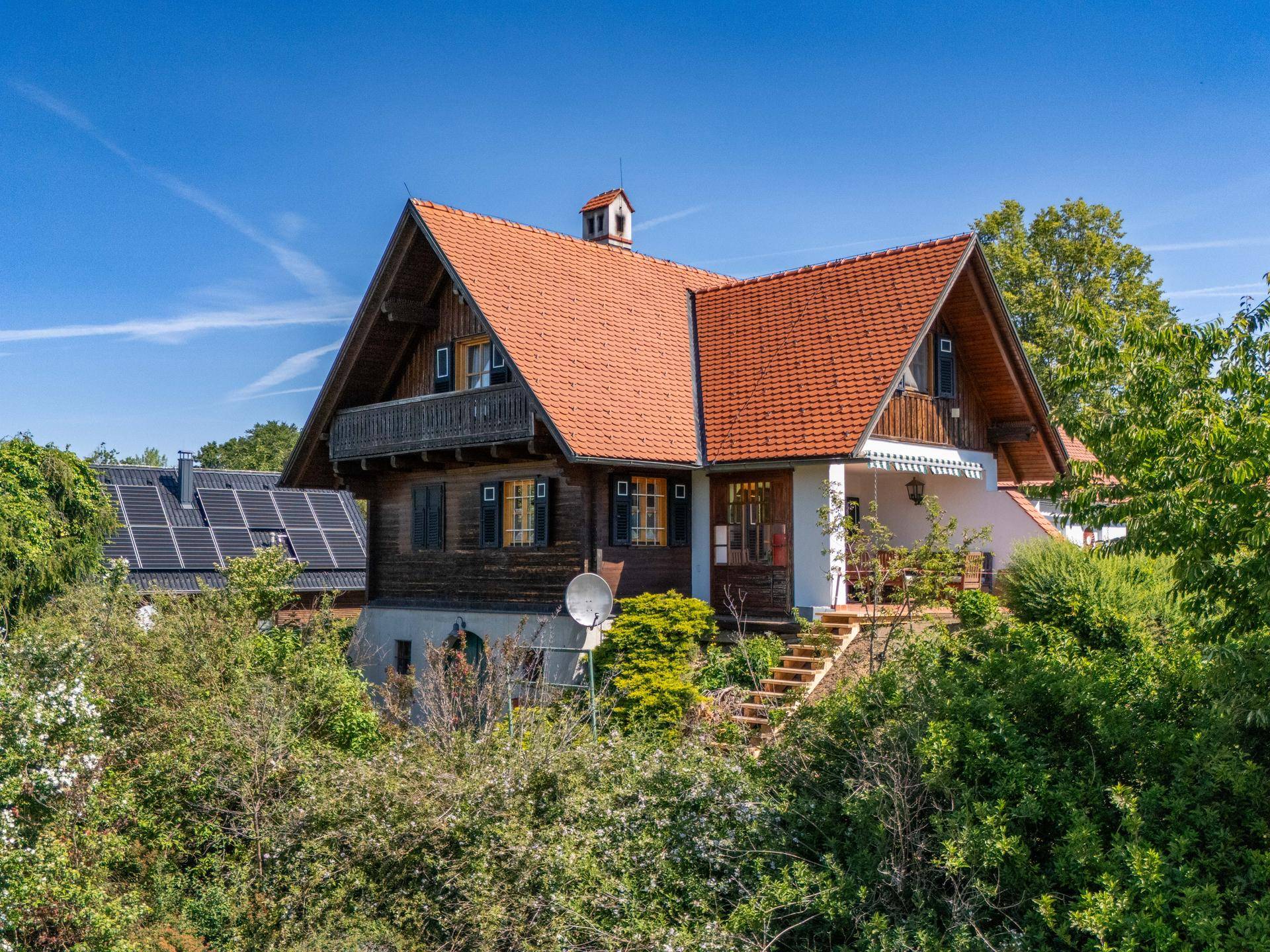 Traditionelles Chalet-Haus mit Holzfassade, rotem Ziegeldach und umgebender Natur.