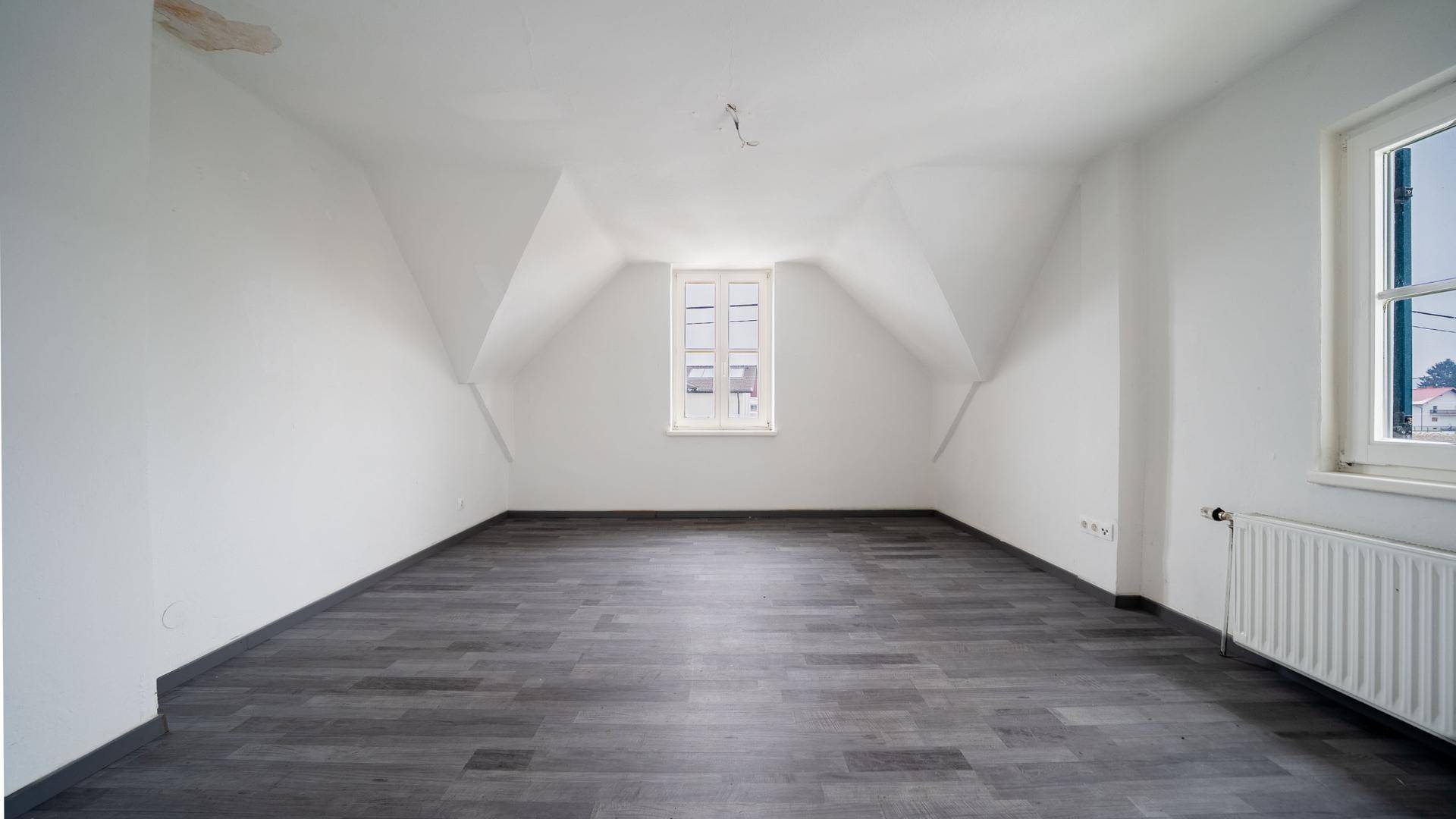 Geräumiges Dachzimmer mit Laminatboden und zwei Fenstern, die für gute Belichtung sorgen.