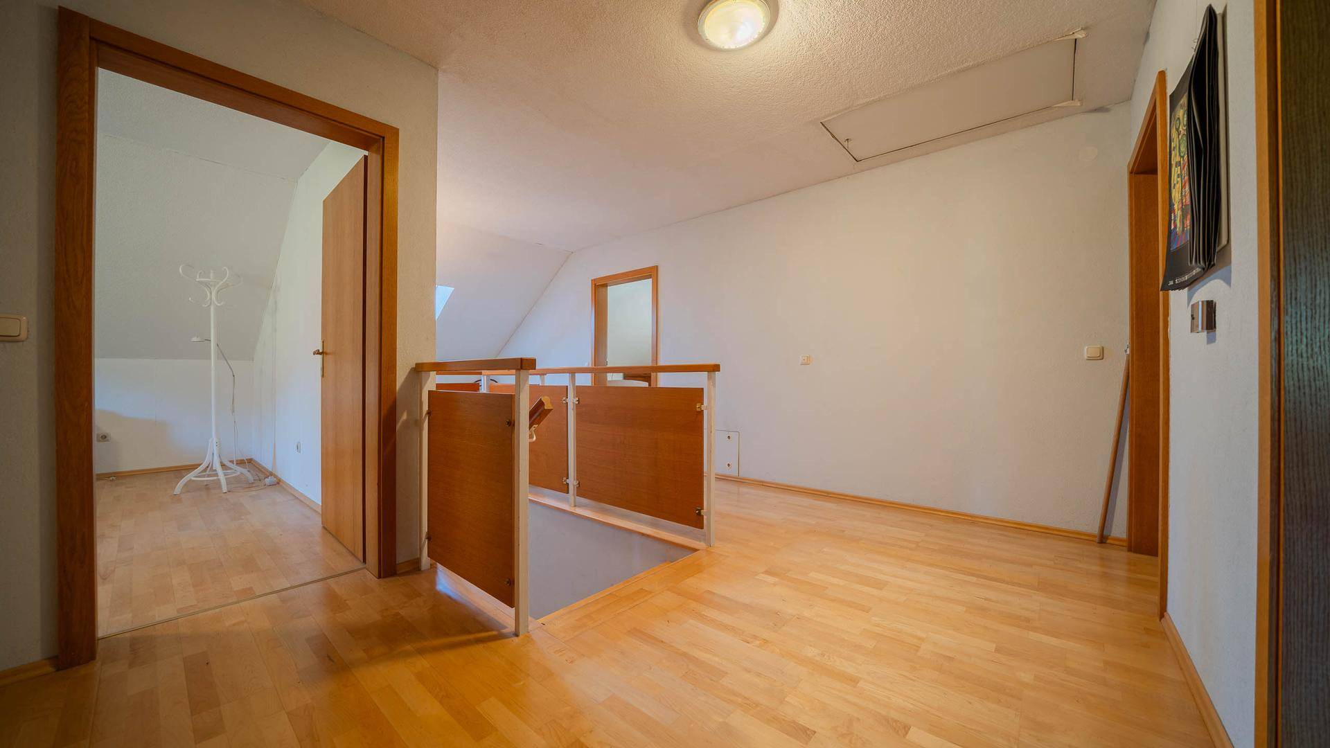 Heller Flur im Obergeschoss mit Holzparkettboden und Dachschrägen.