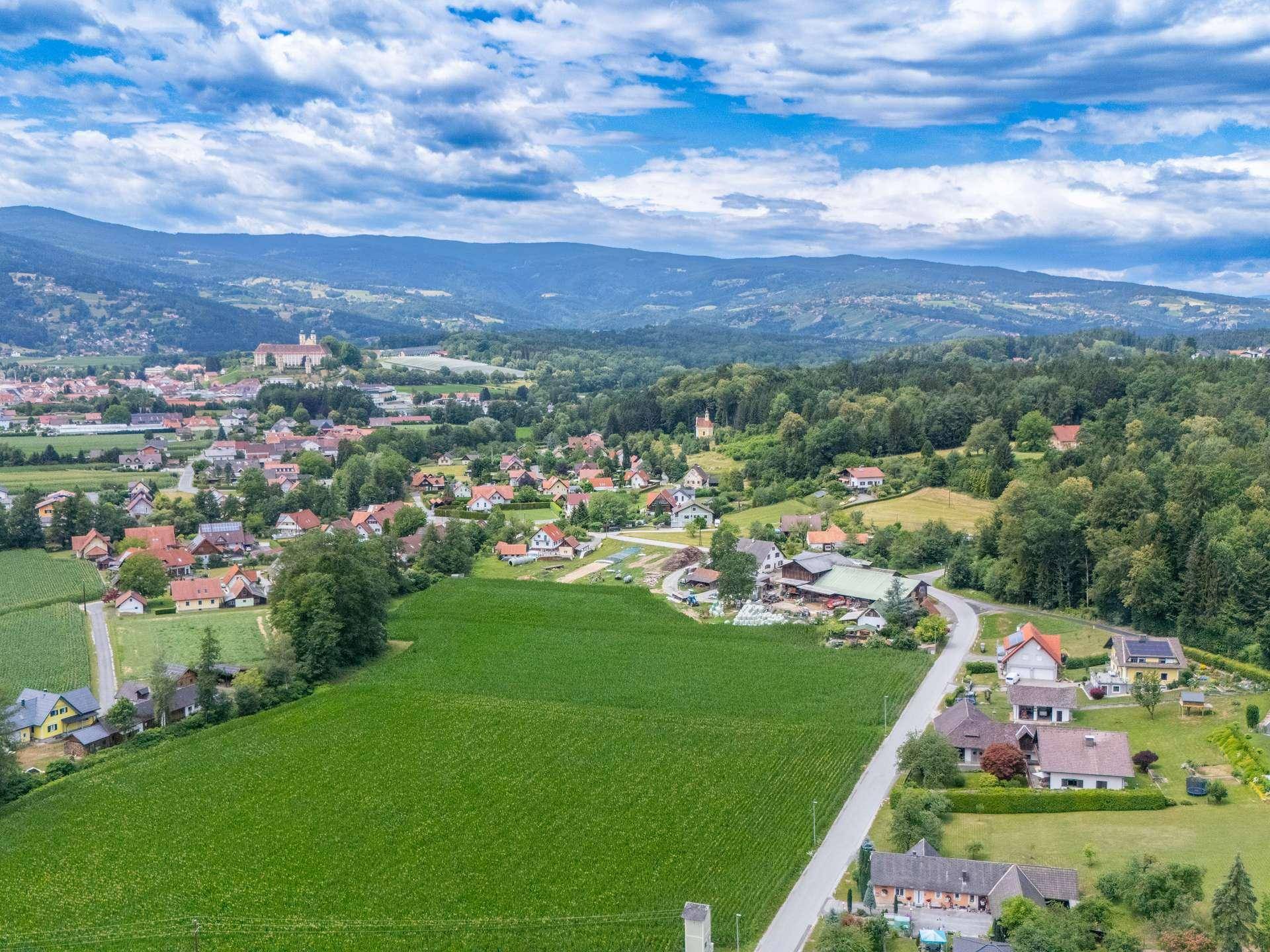 Weitläufige Luftaufnahme einer ländlichen Gegend mit Feldern, Häusern und Bergen.