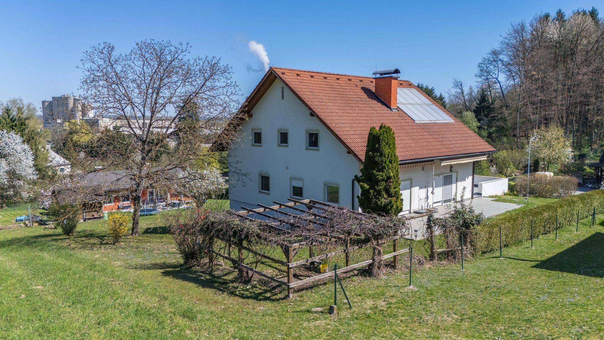 Rückansicht des Hauses mit Photovoltaikanlage, Pergola und großem Gartenbereich.