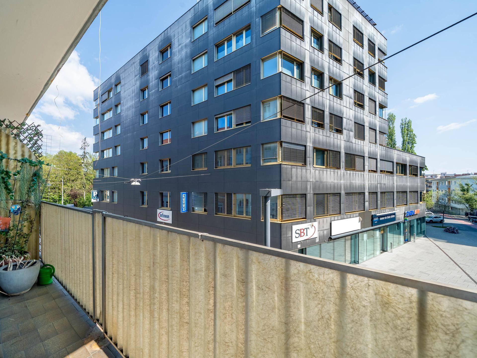 Moderne Gebäudefassade mit vielen Fenstern und Geschäften im Erdgeschoss.