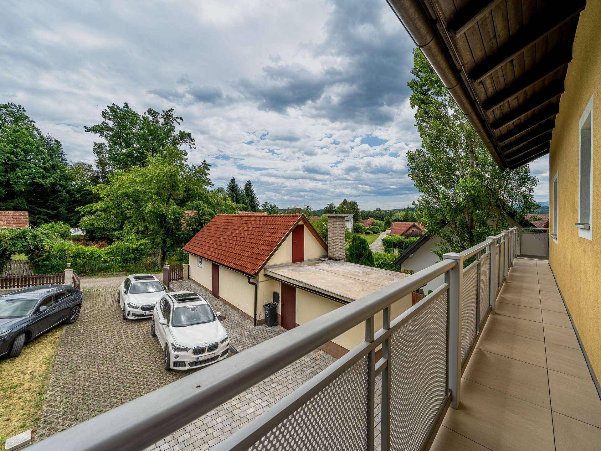 Balkon mit Blick auf den Hof, Parkplätze und die umliegende Landschaft.
