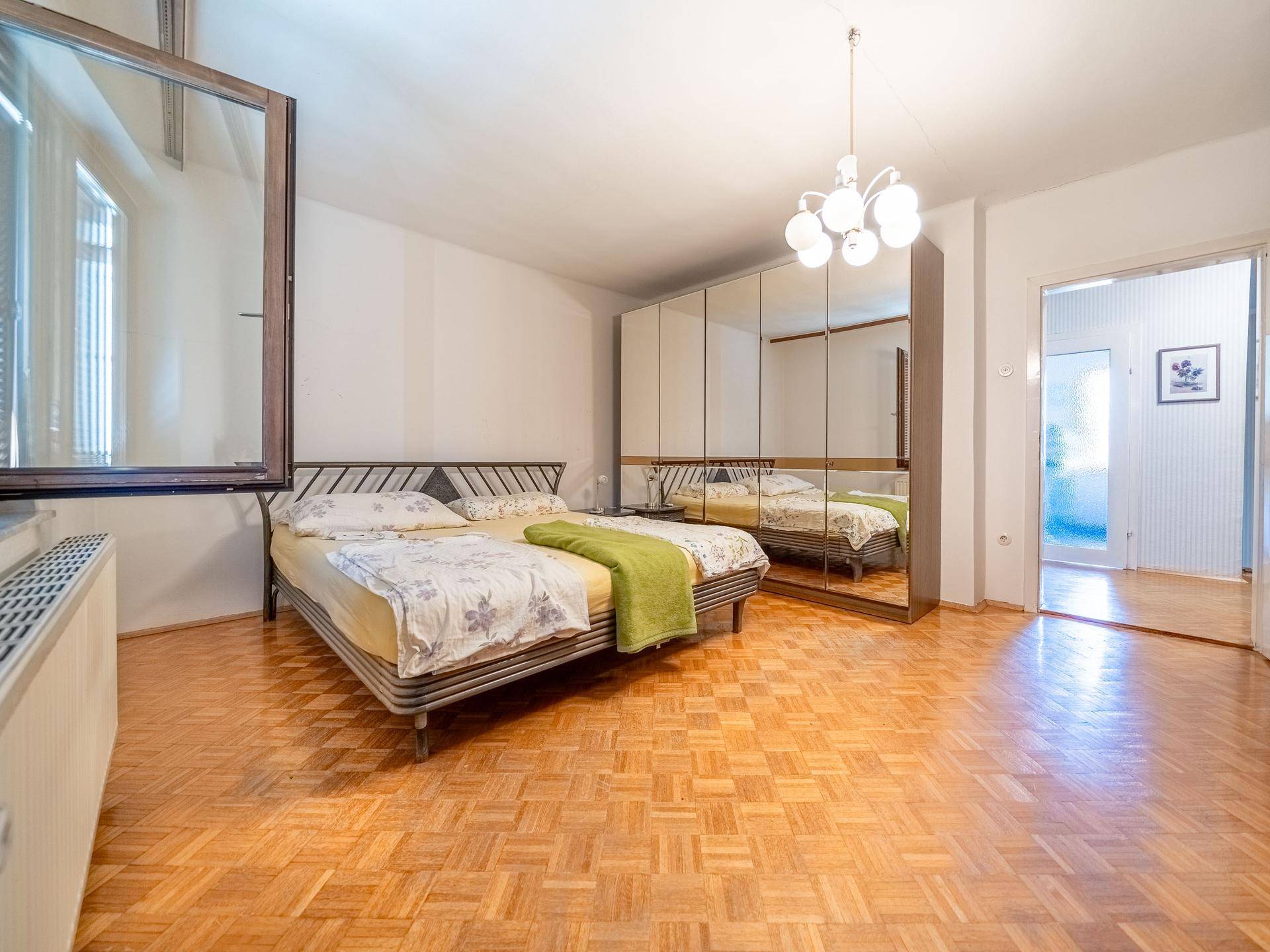 Geräumiges Schlafzimmer mit Parkettboden, großem Spiegelschrank und Doppelbett.