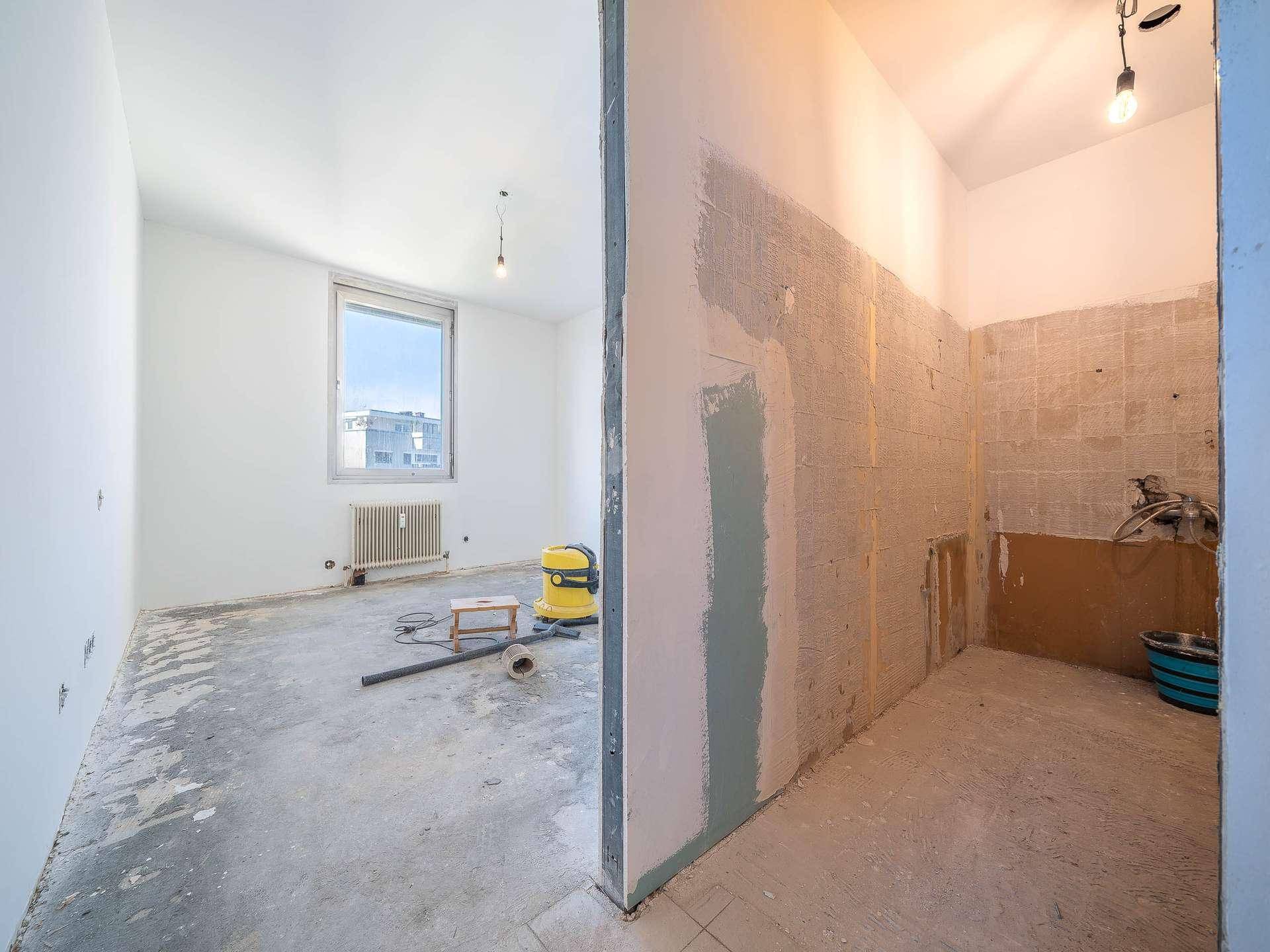 Renovierungsbedürftiger Bereich mit angrenzendem Zimmer und freigelegten Wänden, bereit für den Ausbau.