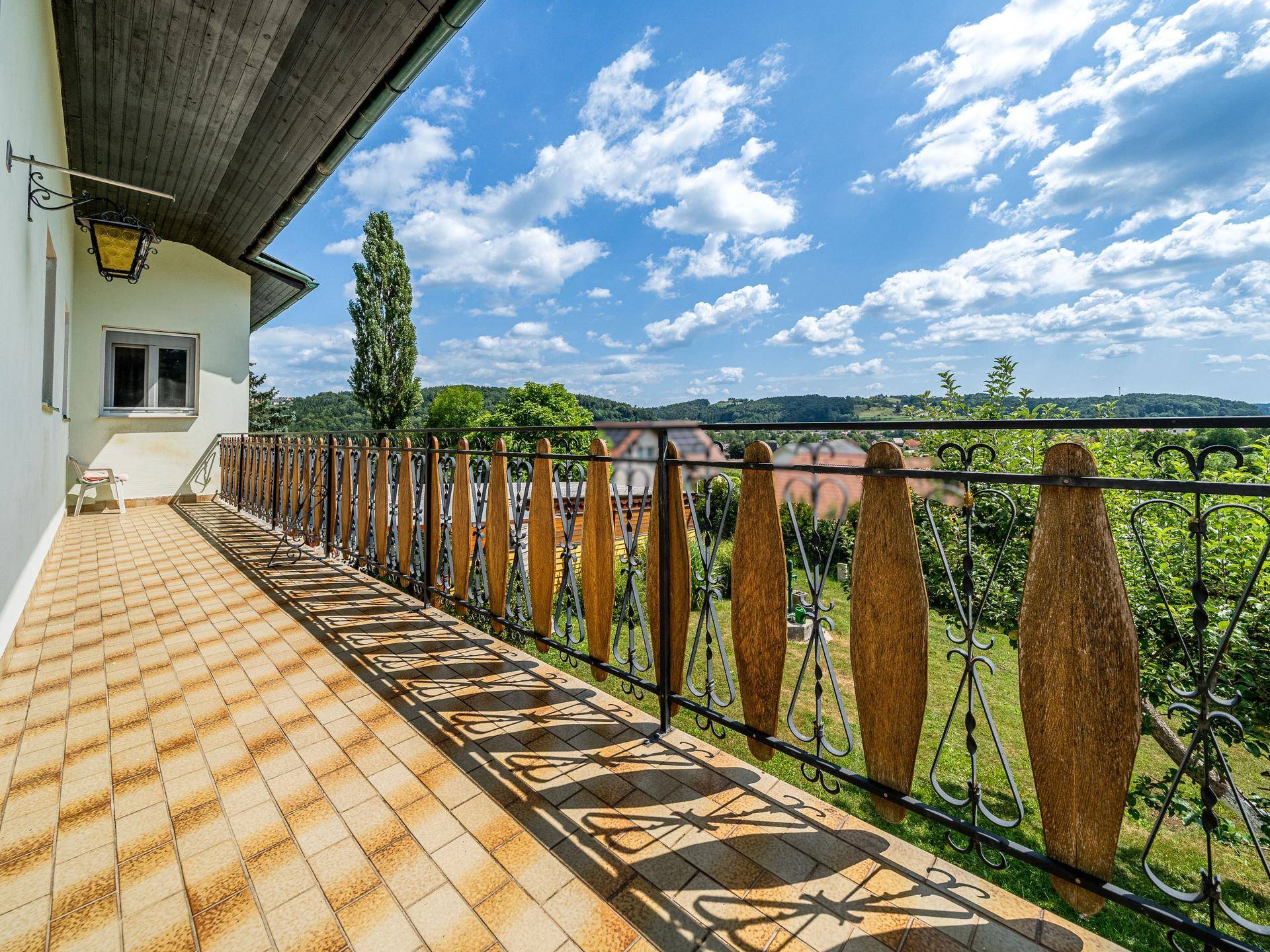 Langer Balkon mit schmiedeeisernem Geländer und weitem Blick über die Landschaft.