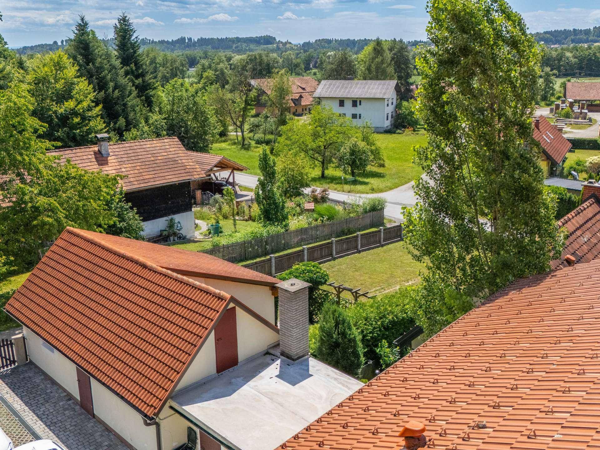 Luftaufnahme des Anwesens mit Ziegeldächern, Flachdach und umliegender grüner Landschaft.