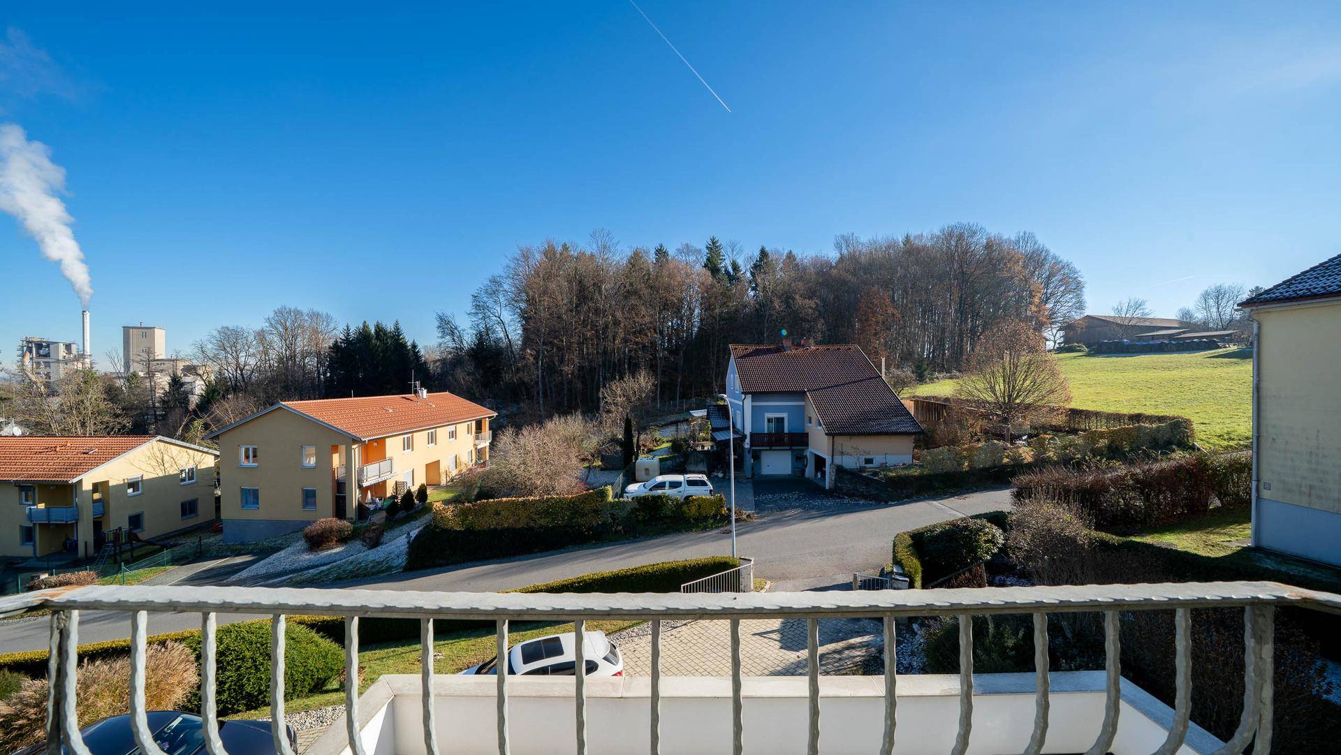 Balkon mit Blick auf die ländliche Umgebung und einen Schornstein in der Ferne.