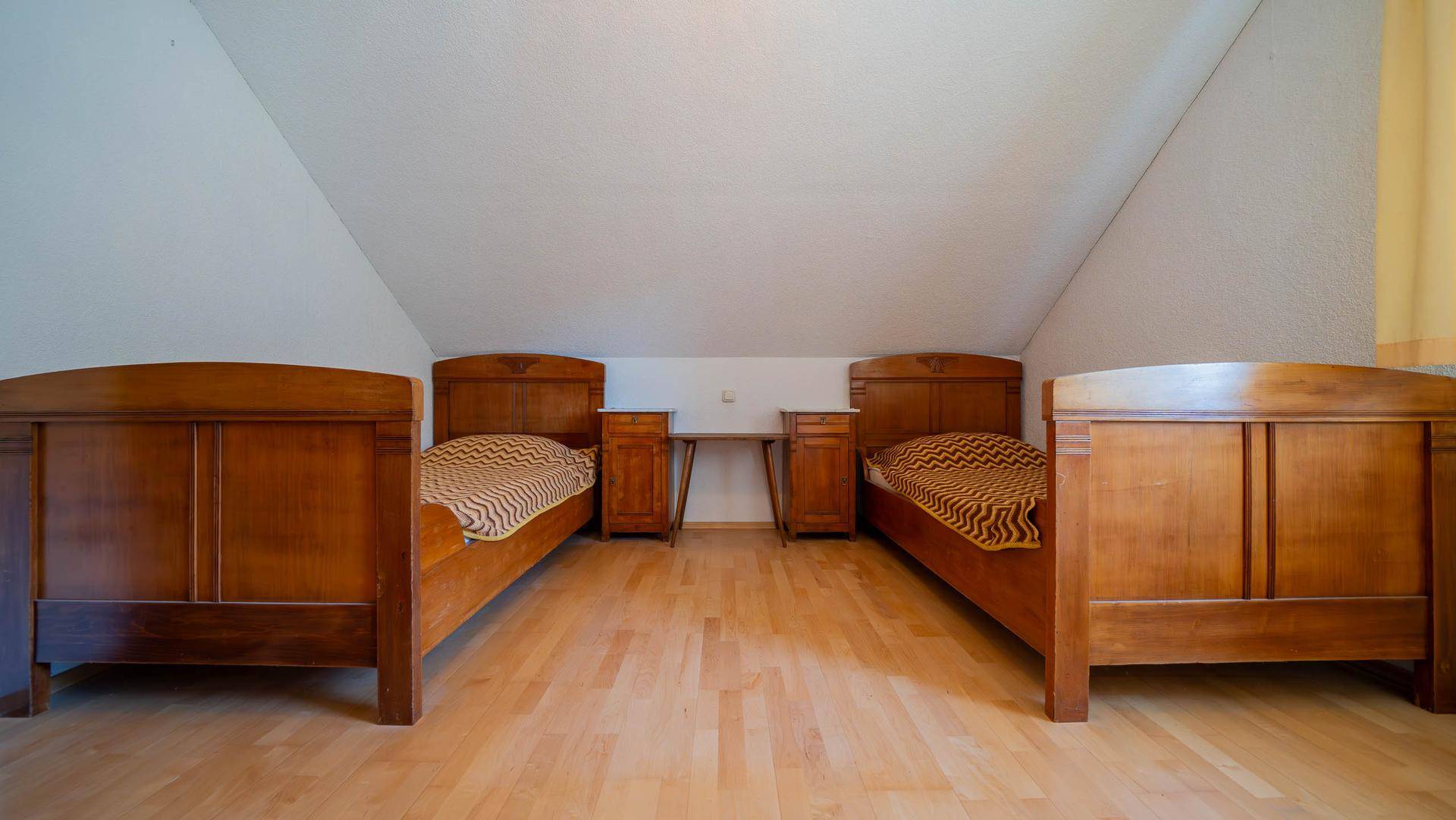 Geräumiges Schlafzimmer im Dachgeschoss mit Holzboden und mehreren Betten.