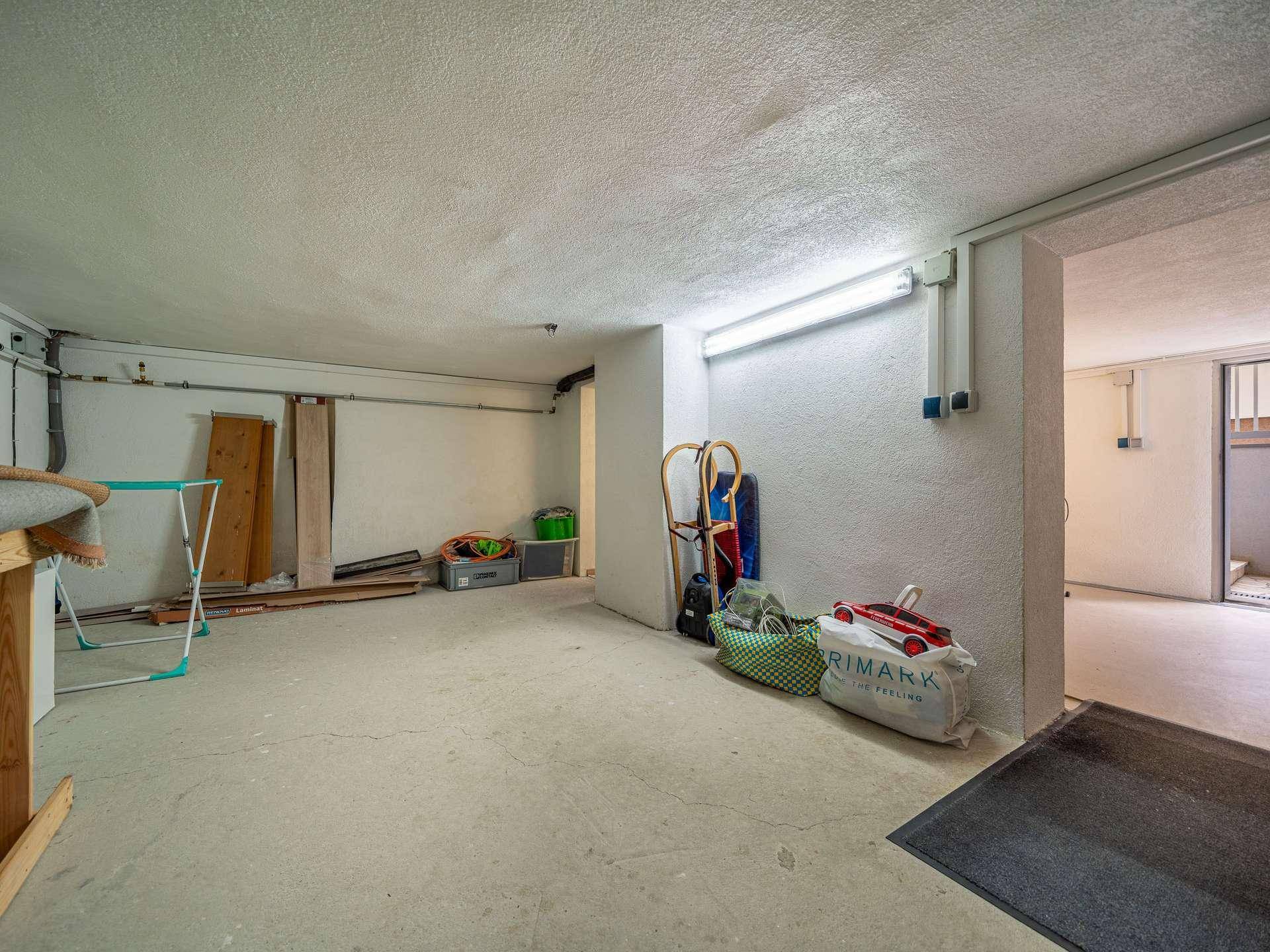 Heller Kellerraum mit Betonboden und Stauraum für diverse Gegenstände.