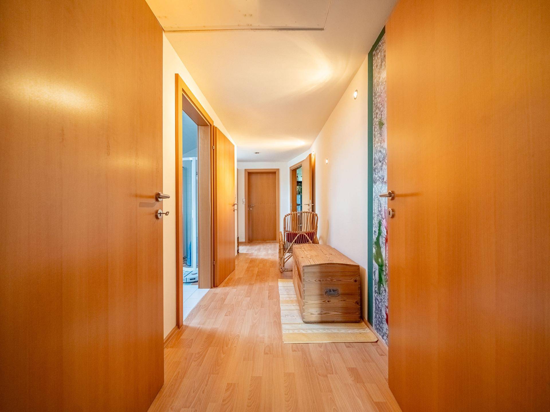 Heller Flur mit Holztüren, Laminatboden und einer rustikalen Holzbank.