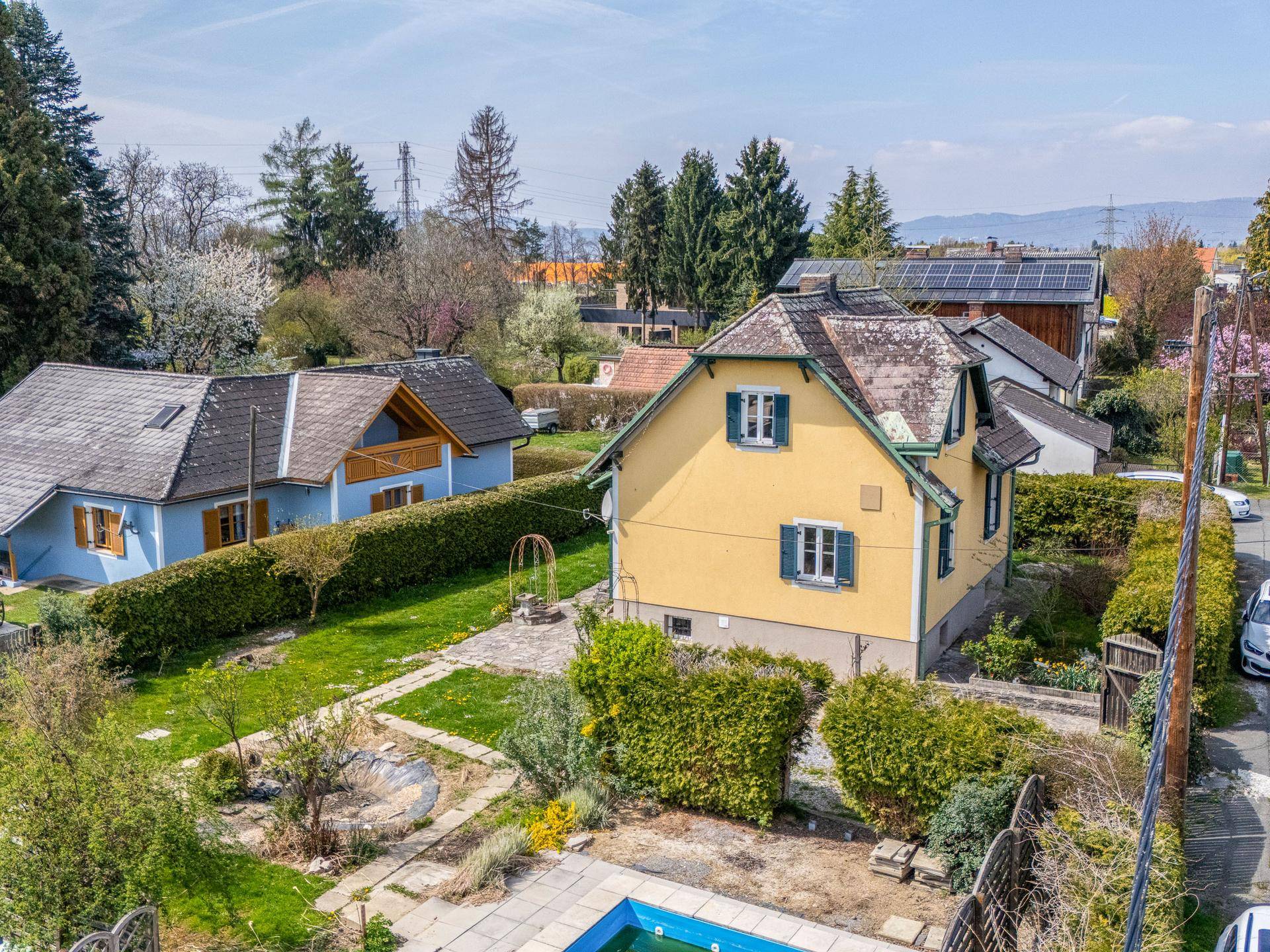 Luftaufnahme des Hauses mit Garten, einem kleinen Pool und angrenzenden Nachbargrundstücken.