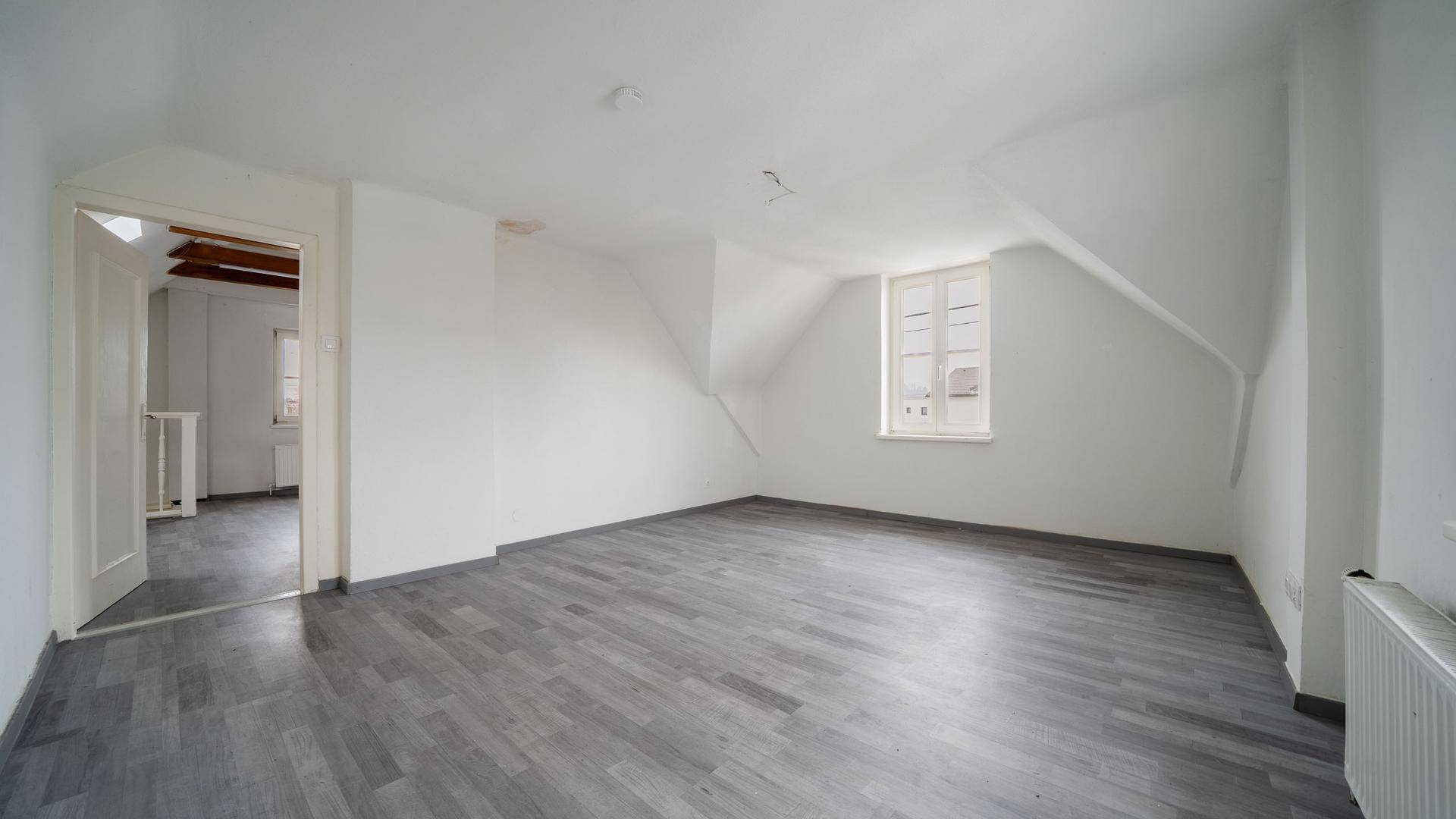 Helles Dachzimmer mit Laminatboden und schrägen Wänden, bietet viel Potenzial für individuelle Gestaltung.