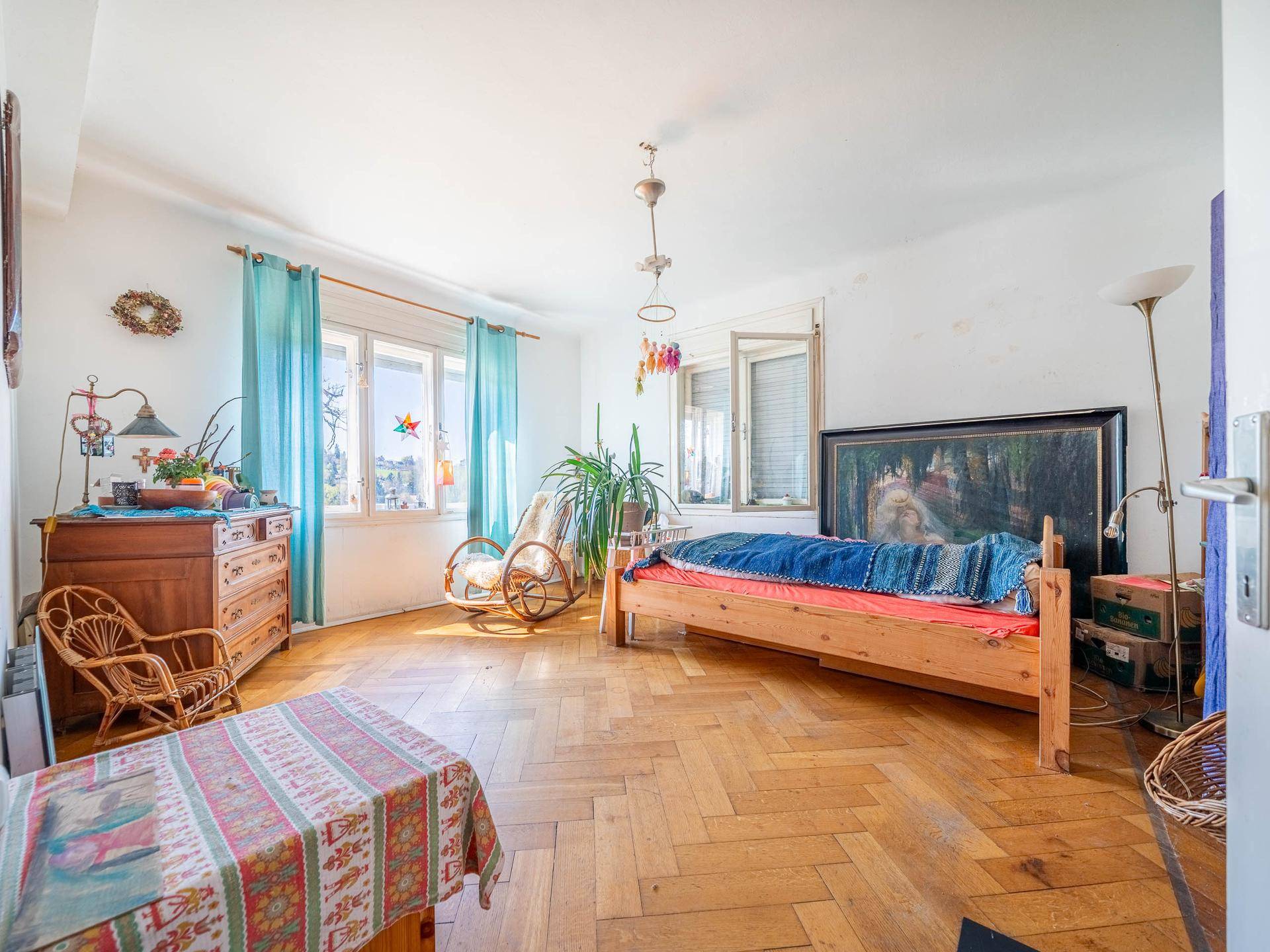 Geräumiges Schlafzimmer mit Parkettboden, Holzbetten und großen Fenstern.