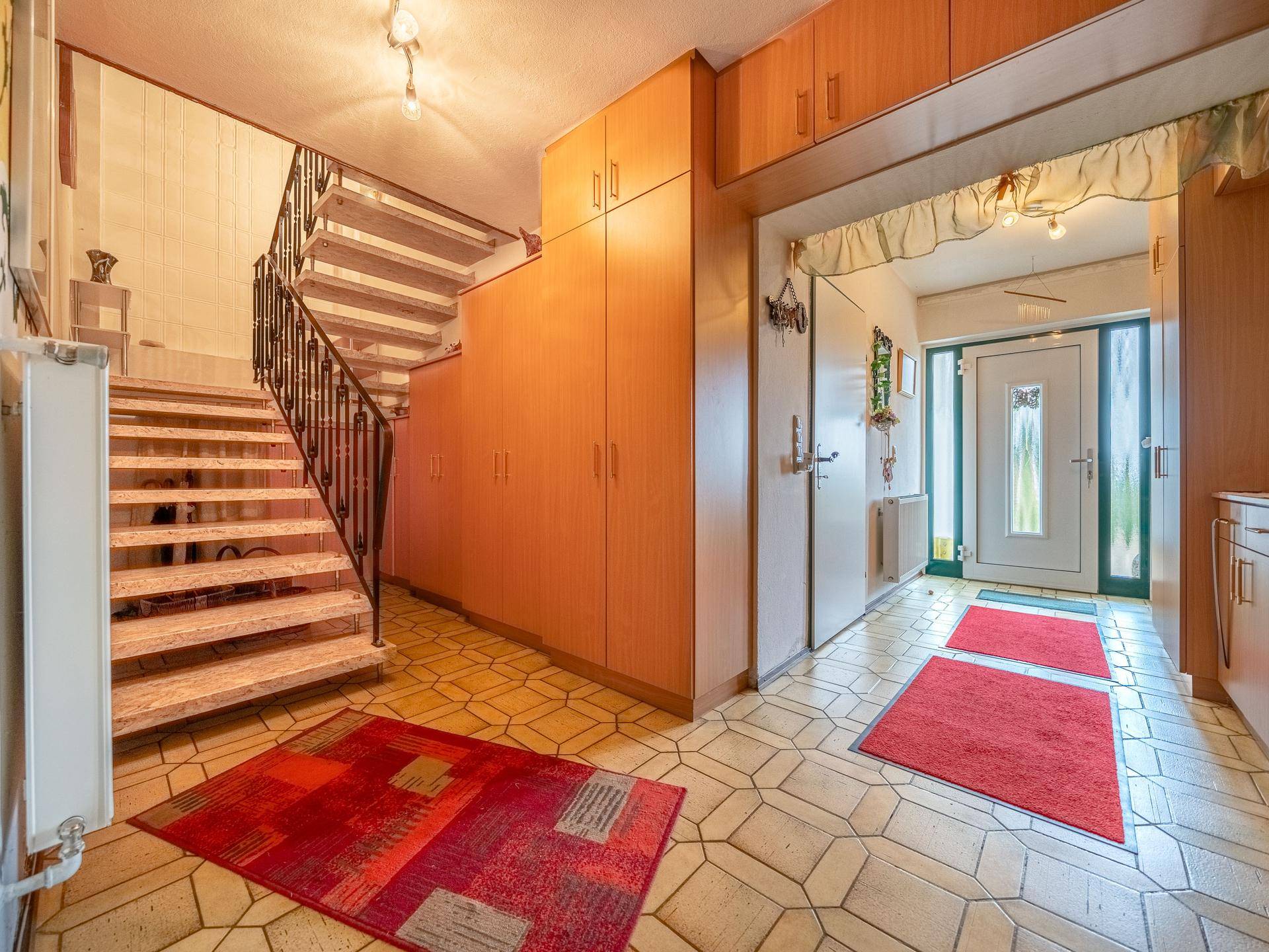 Geräumiger Flur mit Treppe, Einbauschränken und einem gefliesten Boden im Eingangsbereich.