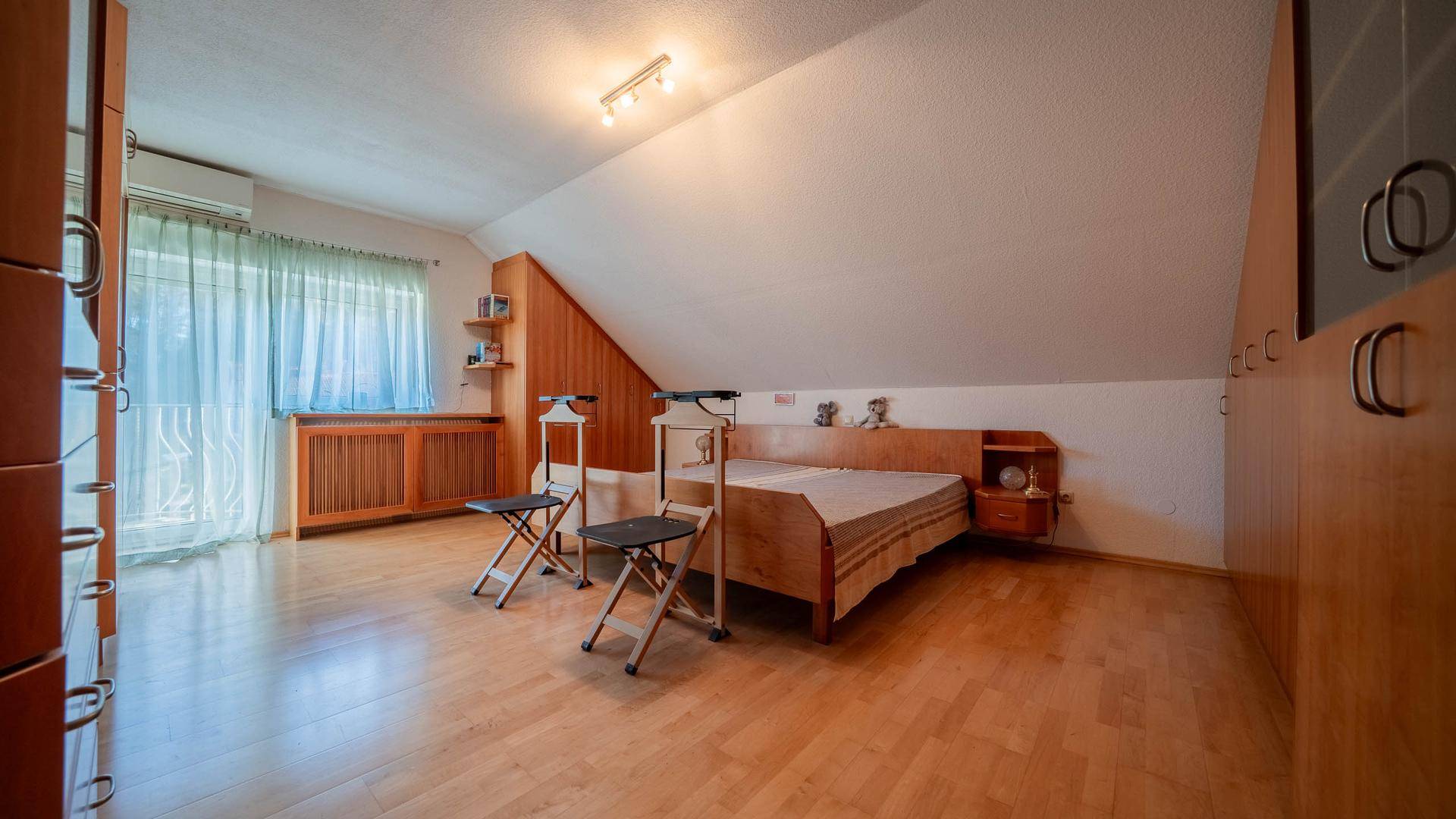 Schlafzimmer im Dachgeschoss mit Holzboden, Dachschräge und Einbauschränken.