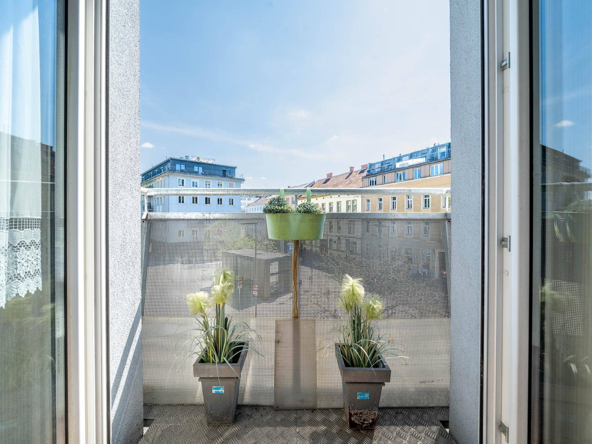 Kleiner Balkon mit Pflanzen und Blick auf die Stadt.