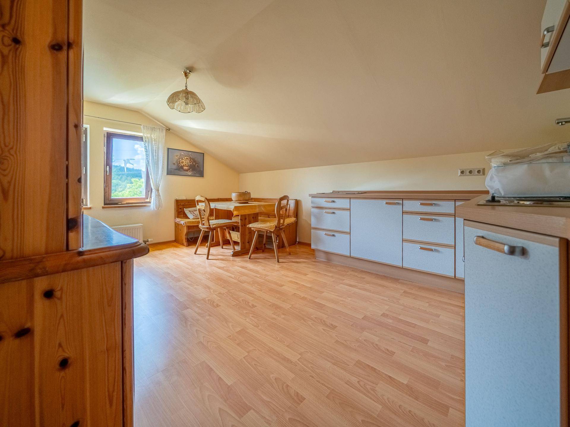 Helle Dachgeschossküche mit Essbank, Laminatboden und Fenster mit Ausblick.