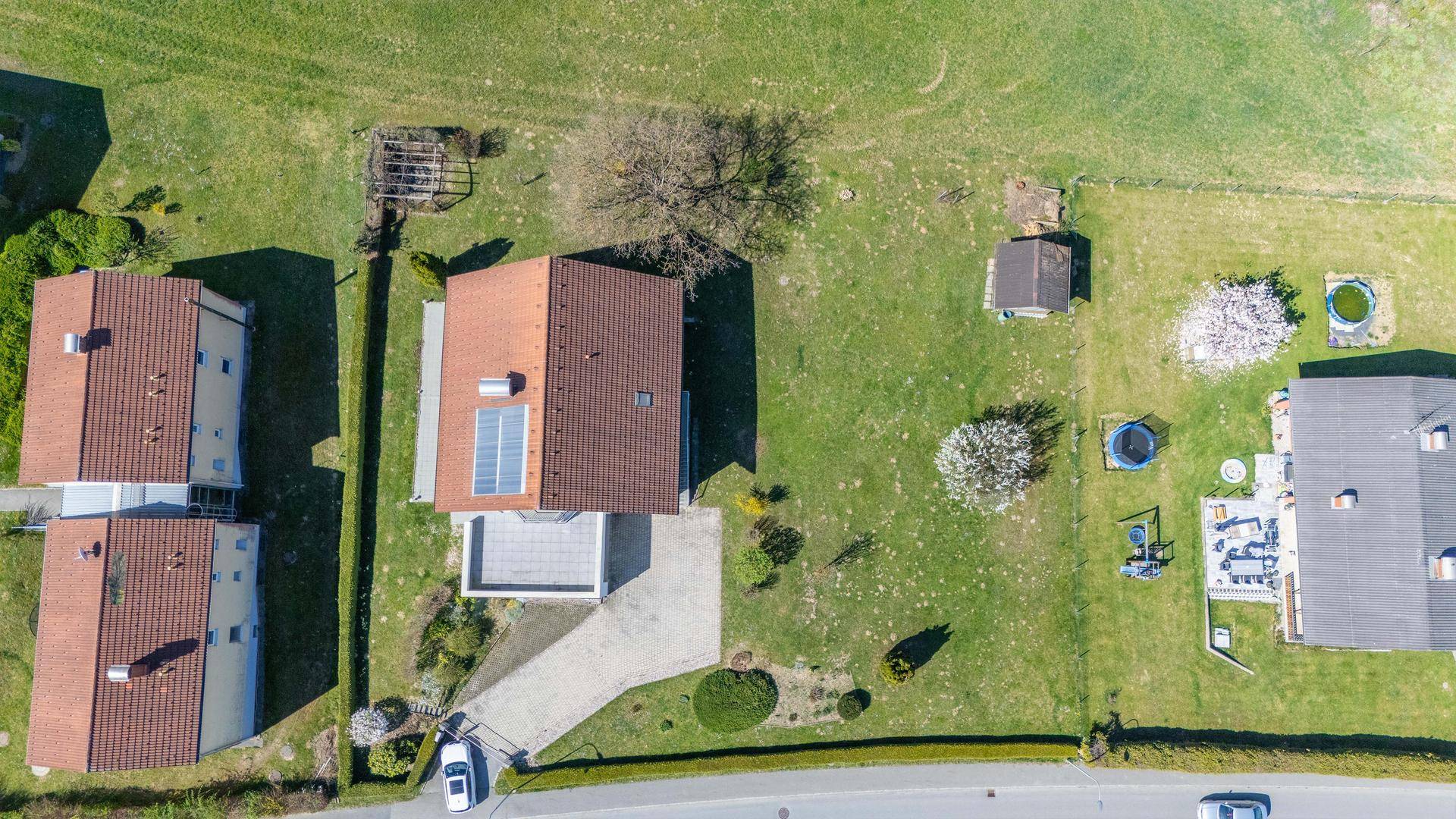 Luftaufnahme des Hauses mit Garten, Photovoltaikanlage auf dem Dach und umliegenden Grundstücken.