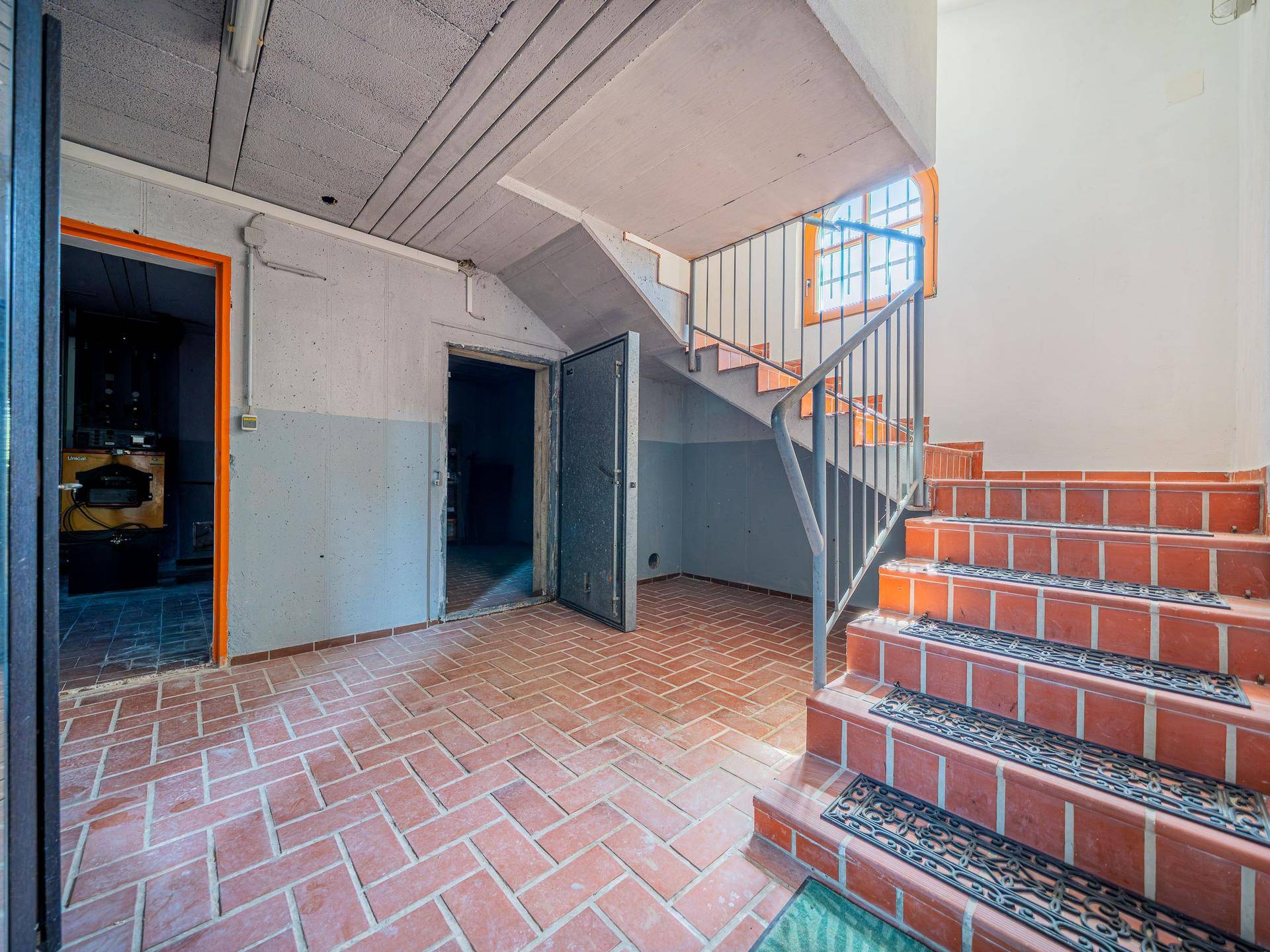 Kellerflur mit Ziegelfliesenboden und Treppe, die in die oberen Etagen des Hauses führt.