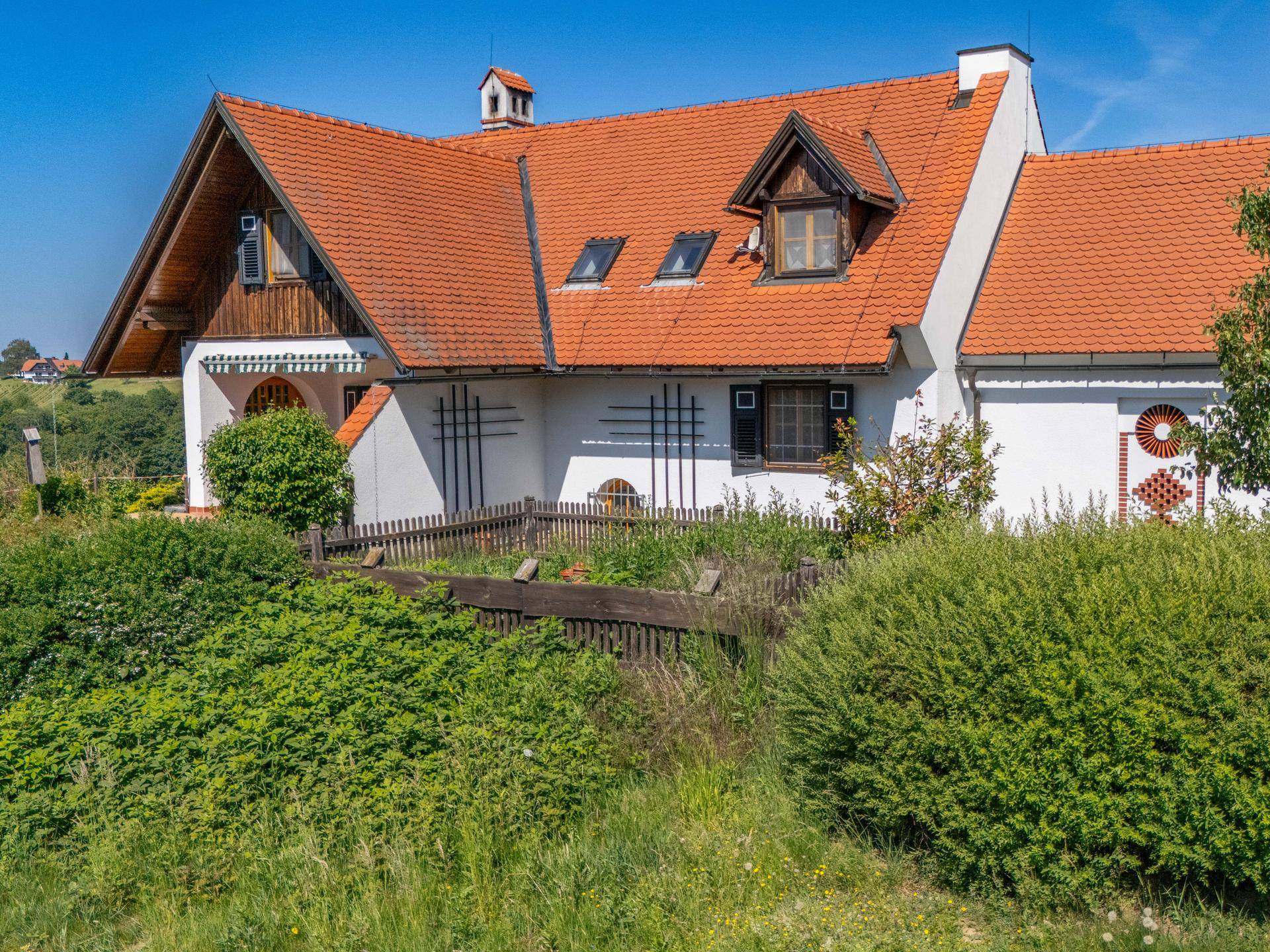 Seitenansicht des Hauses mit kleinem umzäunten Gartenbereich und Dachgauben.