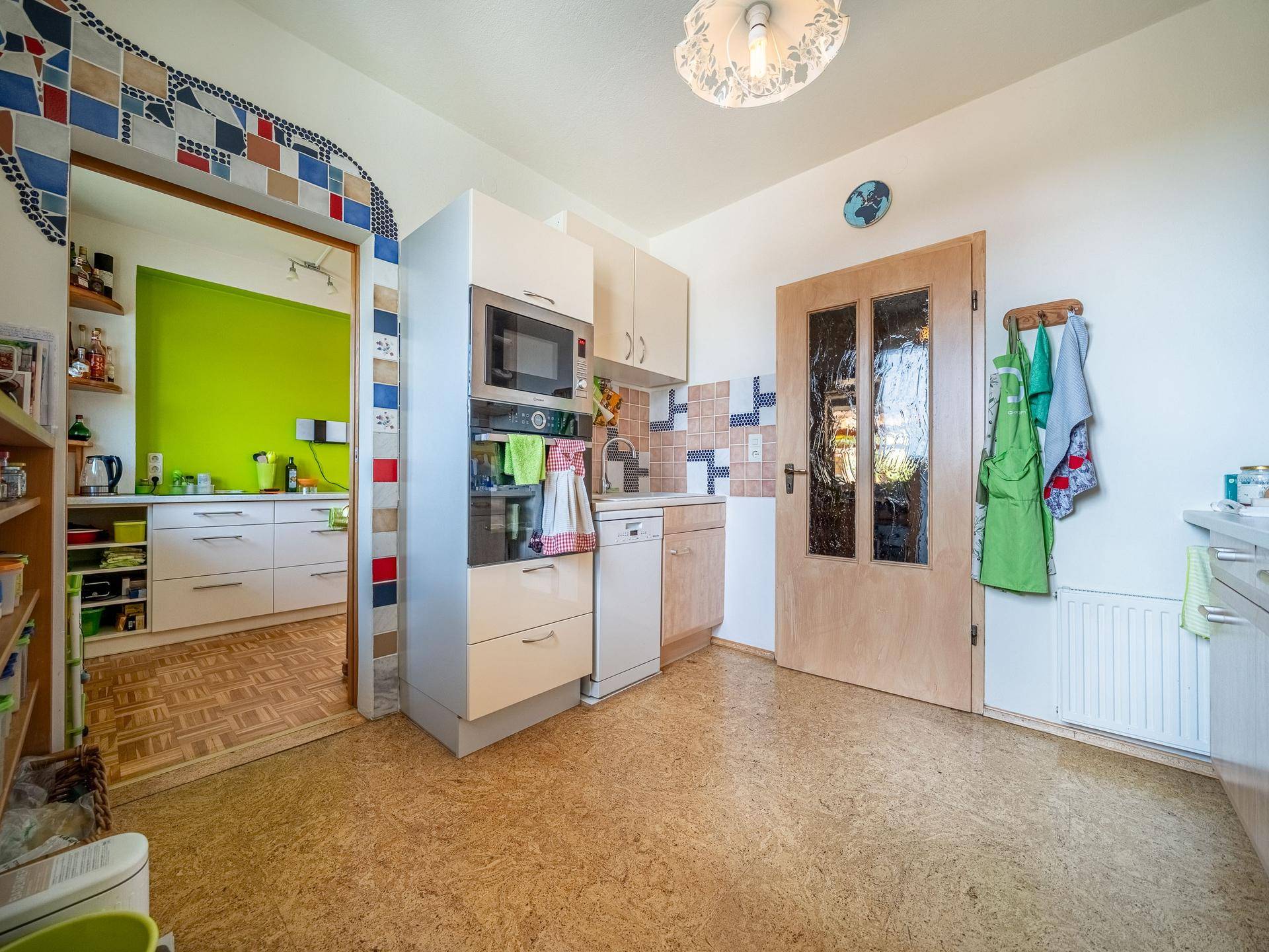Kleine Küche mit Mikrowelle, Spülbecken und Zugang zum Hauptküchenbereich.