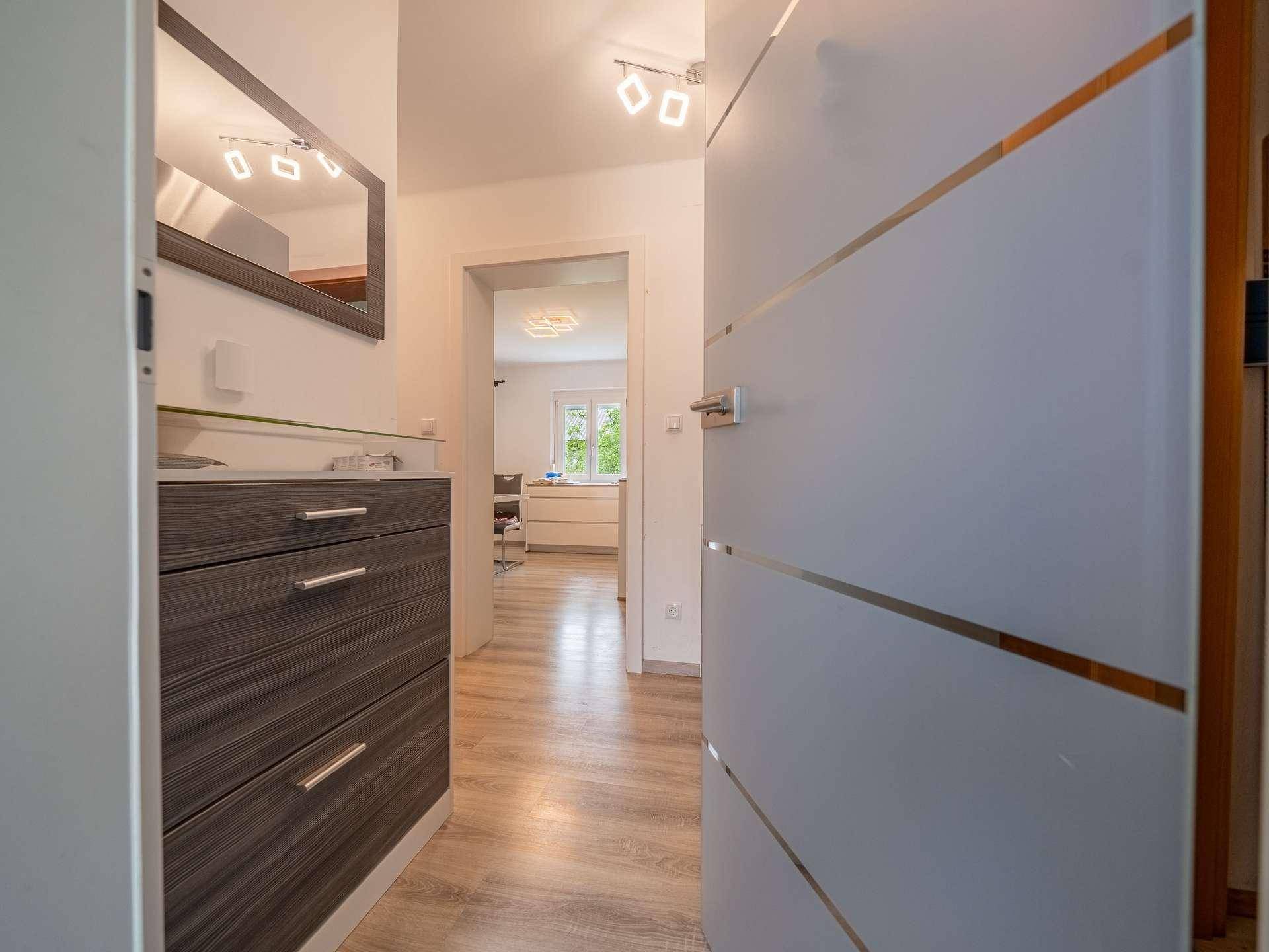 Heller Eingangsbereich mit modernem Schuhschrank und Blick in den Wohnbereich.