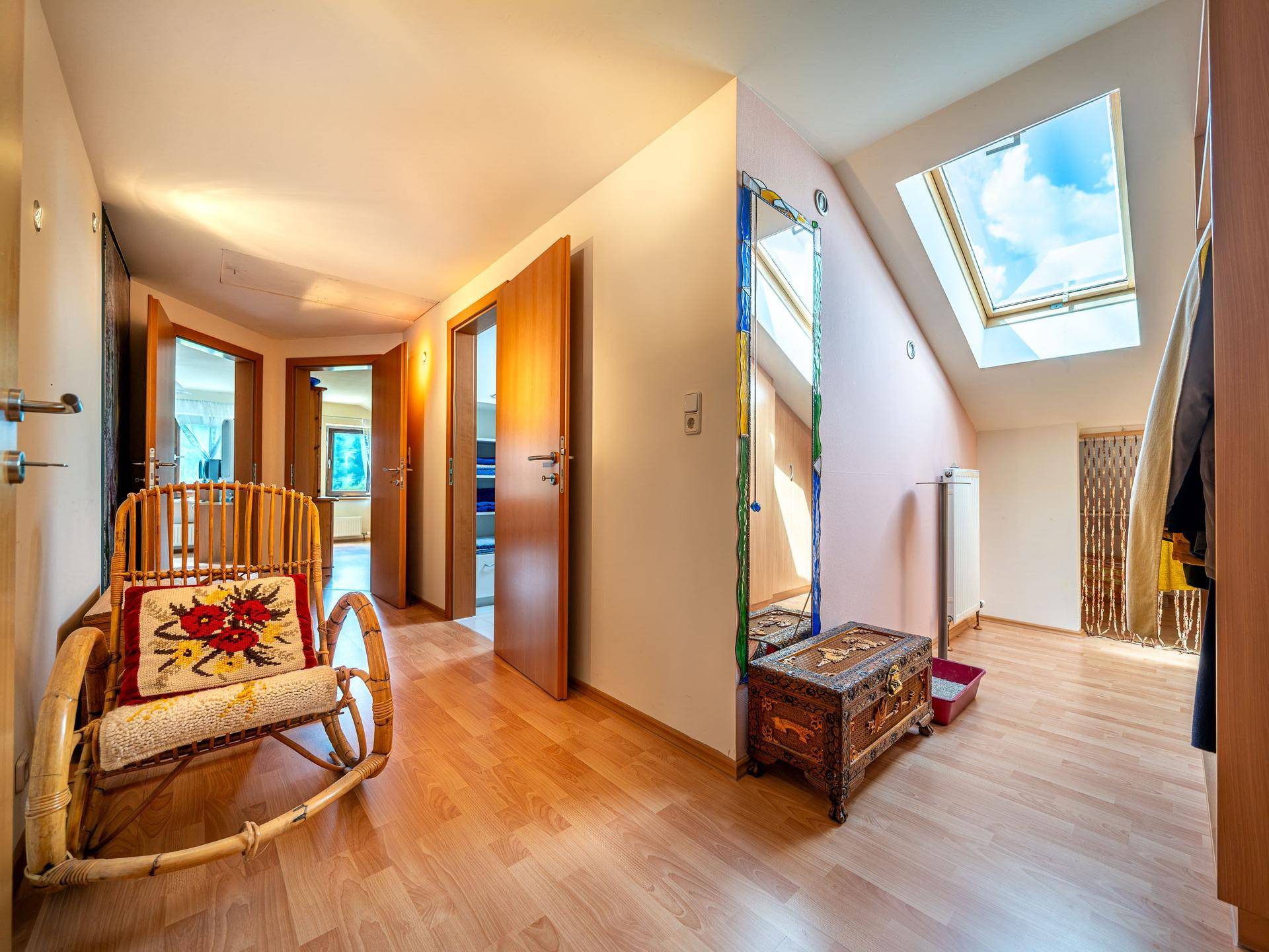 Heller Dachgeschossflur mit Laminatboden, Dachfenster und rustikalen Möbeln.