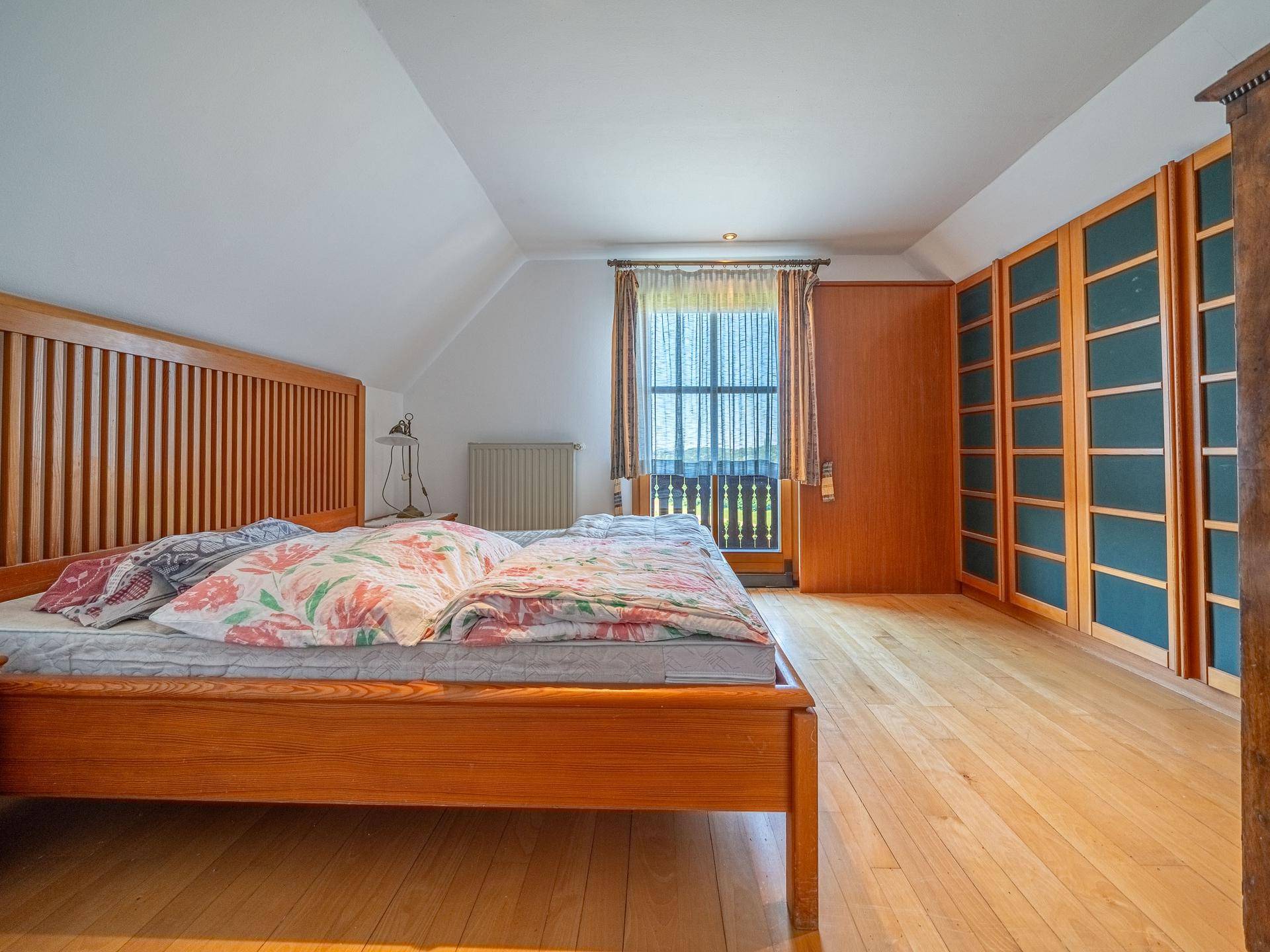 Gemütliches Schlafzimmer mit Holzbett, Einbauschränken und direktem Zugang zum Balkon.