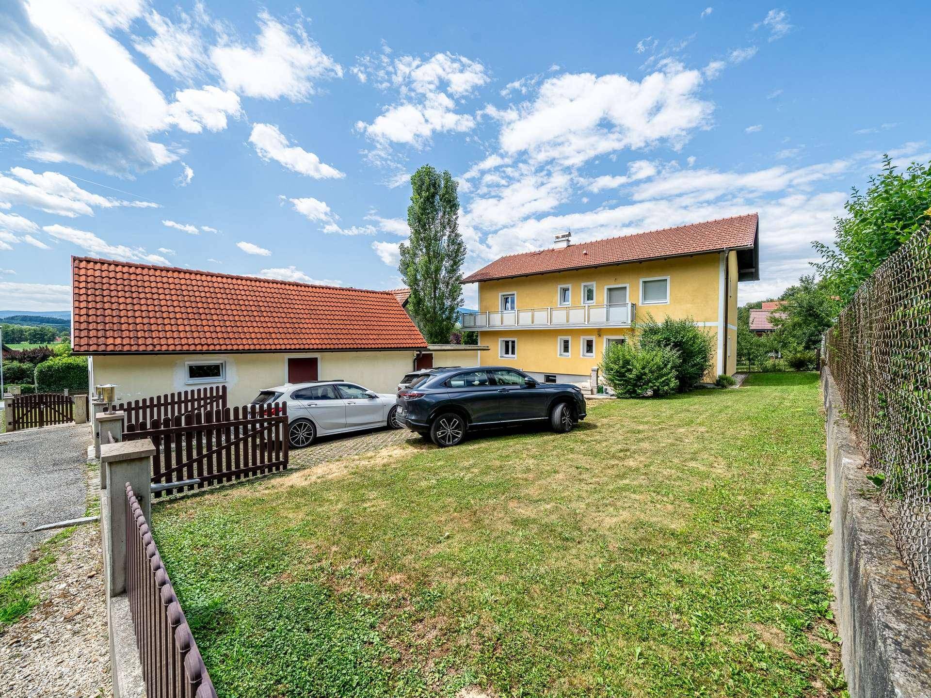 Gesamtansicht des Anwesens mit Haupthaus, Nebengebäude und großem Rasenbereich.
